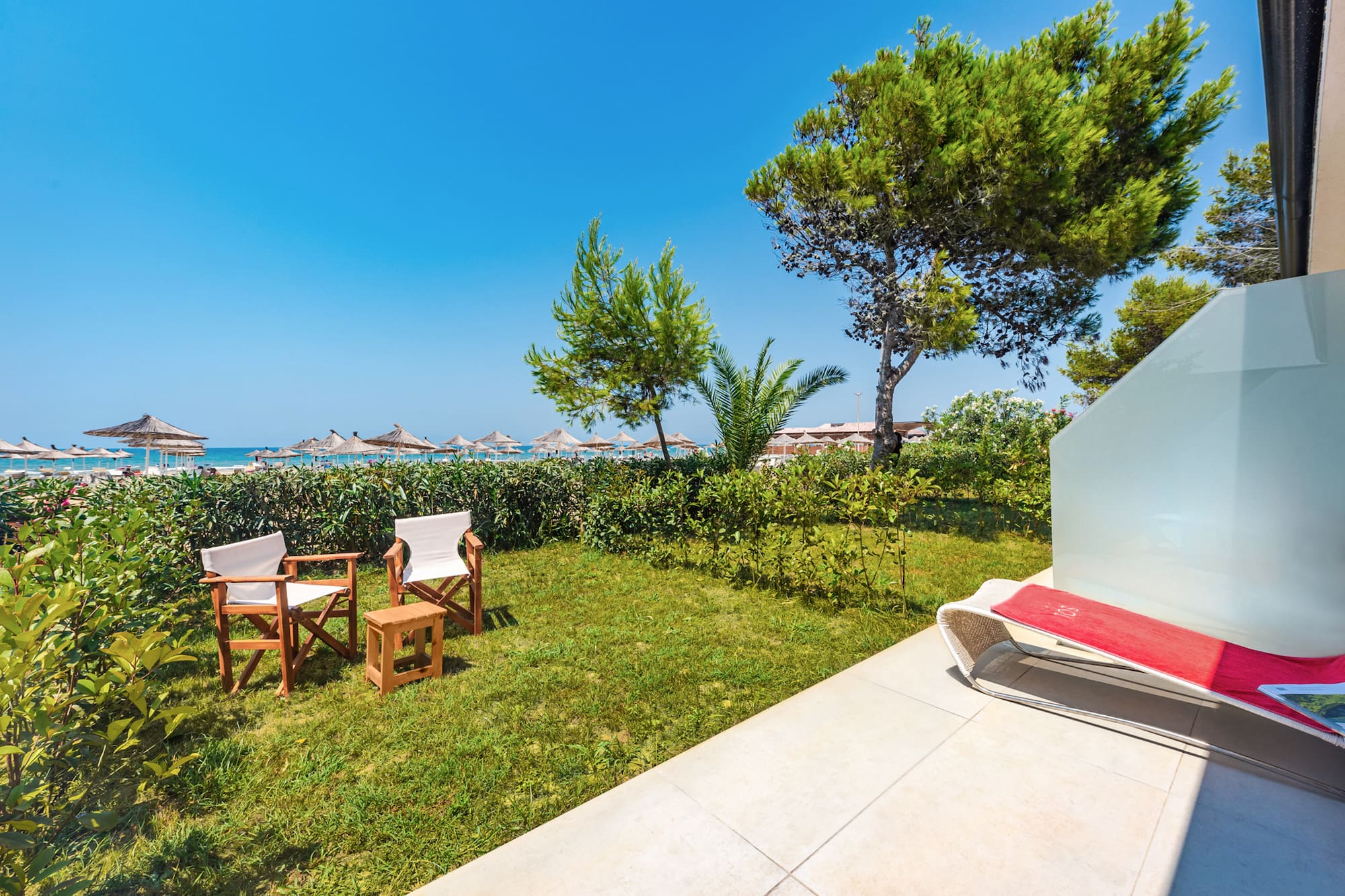 a lawn chair and chairs on a patio by a beach