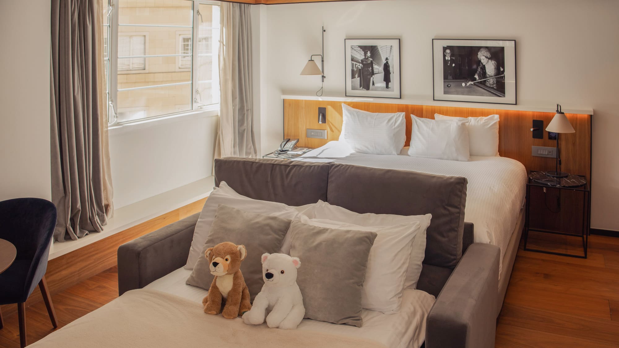 Hotel room with main bed, sofa bed, wooden headboard, and teddy bears.