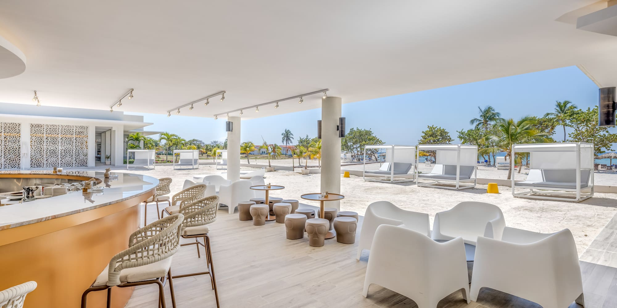 a white patio with chairs and tables on a beach