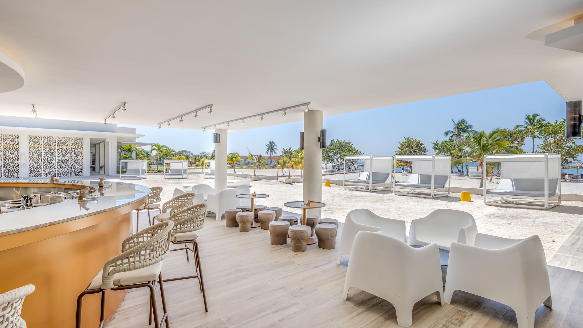 a white patio with chairs and tables on a beach