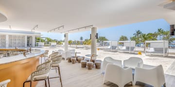 a white patio with chairs and tables on a beach