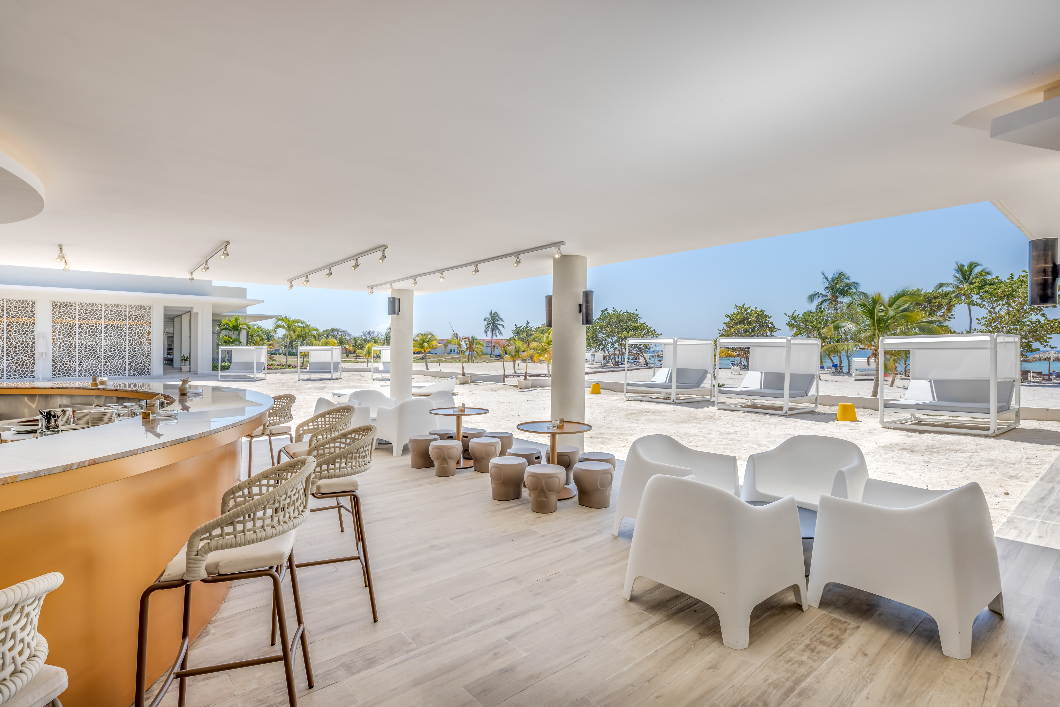 a white patio with chairs and tables on a beach