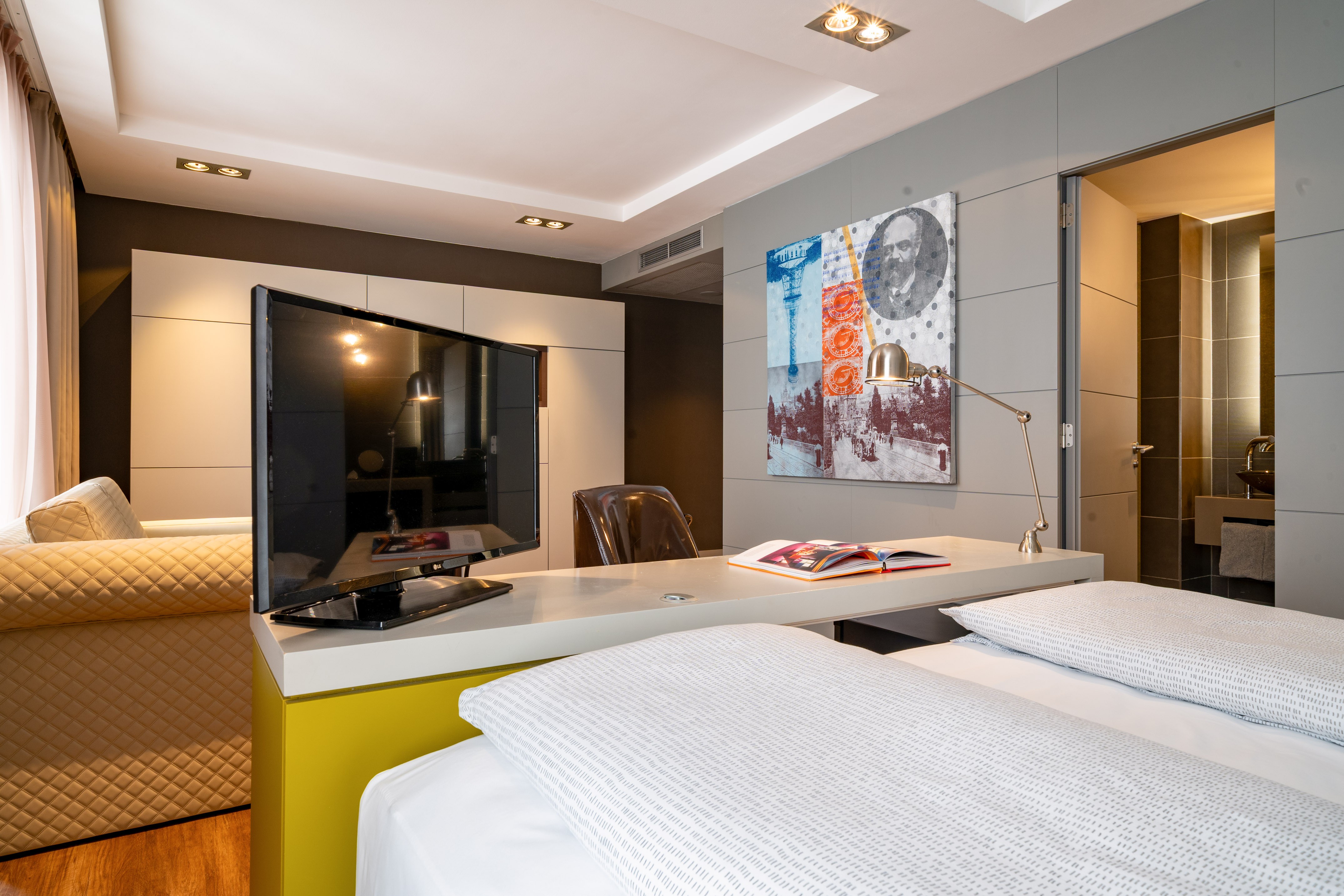 Contemporary hotel room with bed, TV, work desk, and unique wall art.