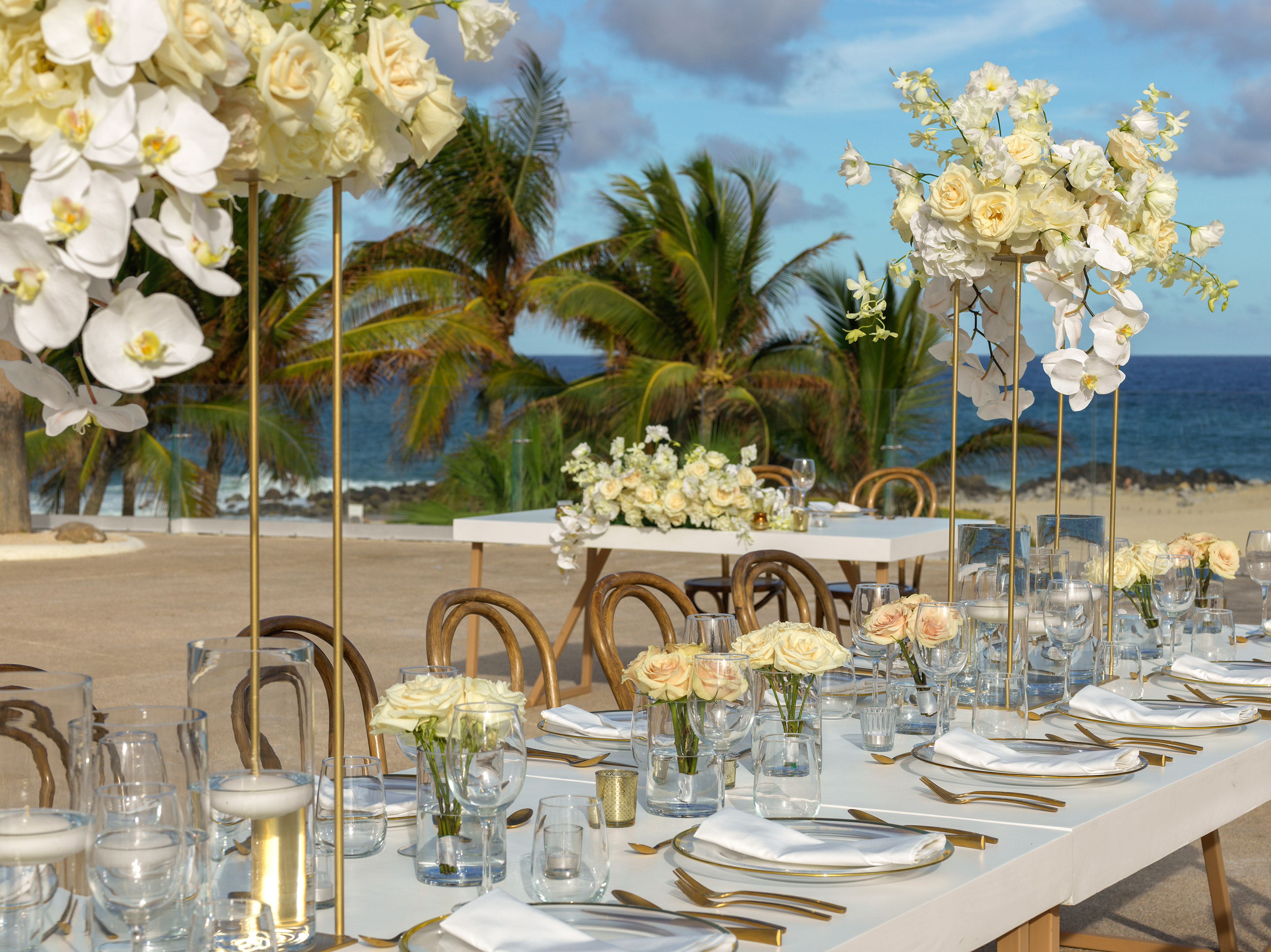 Beach wedding table with white flowers, gold accents, and ocean view. - Terraza Océano 2 - Paradisus Los Cabos - Adults Only, Los Cabos