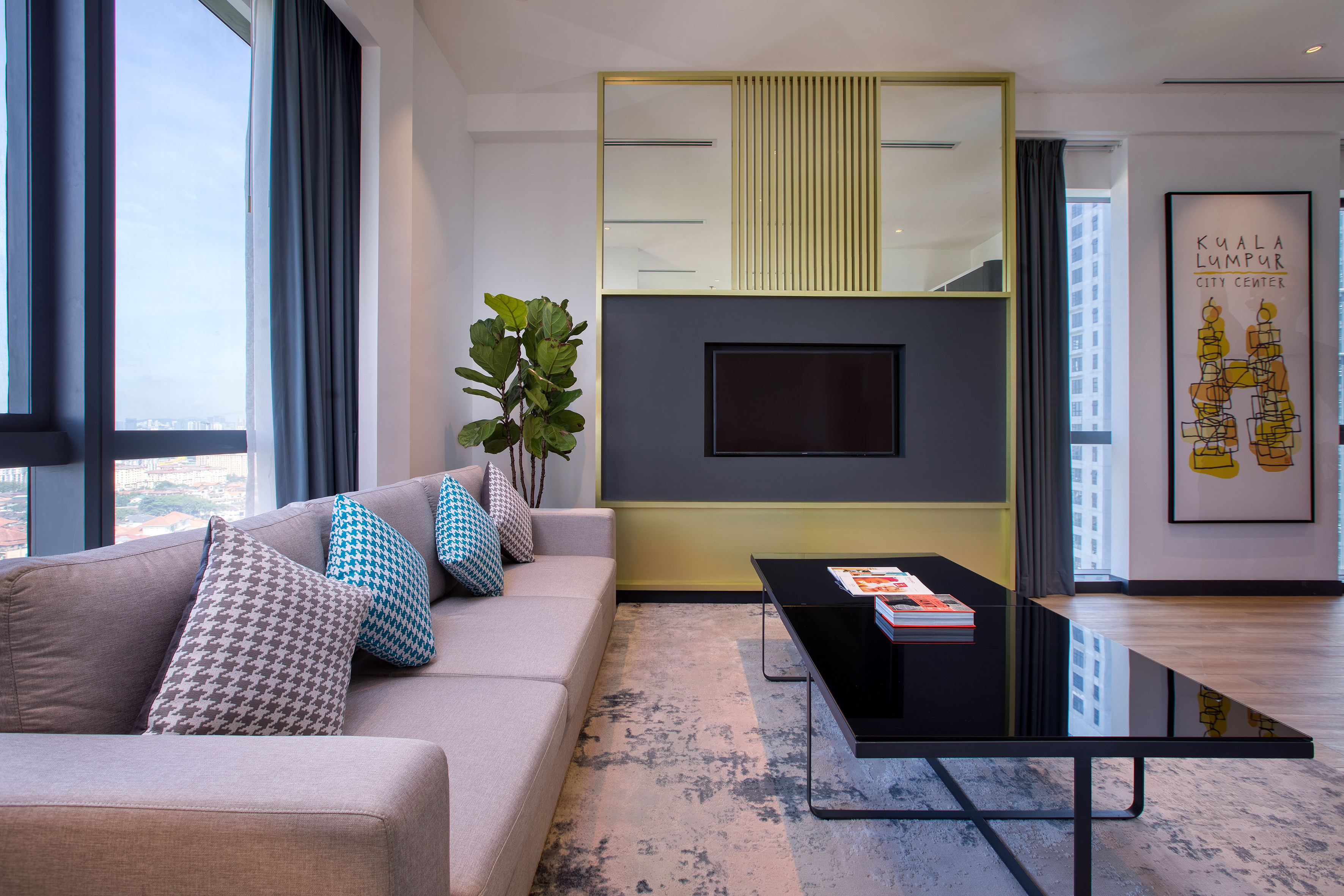 Modern living room with sofa, coffee table, TV, and Kuala Lumpur city view.