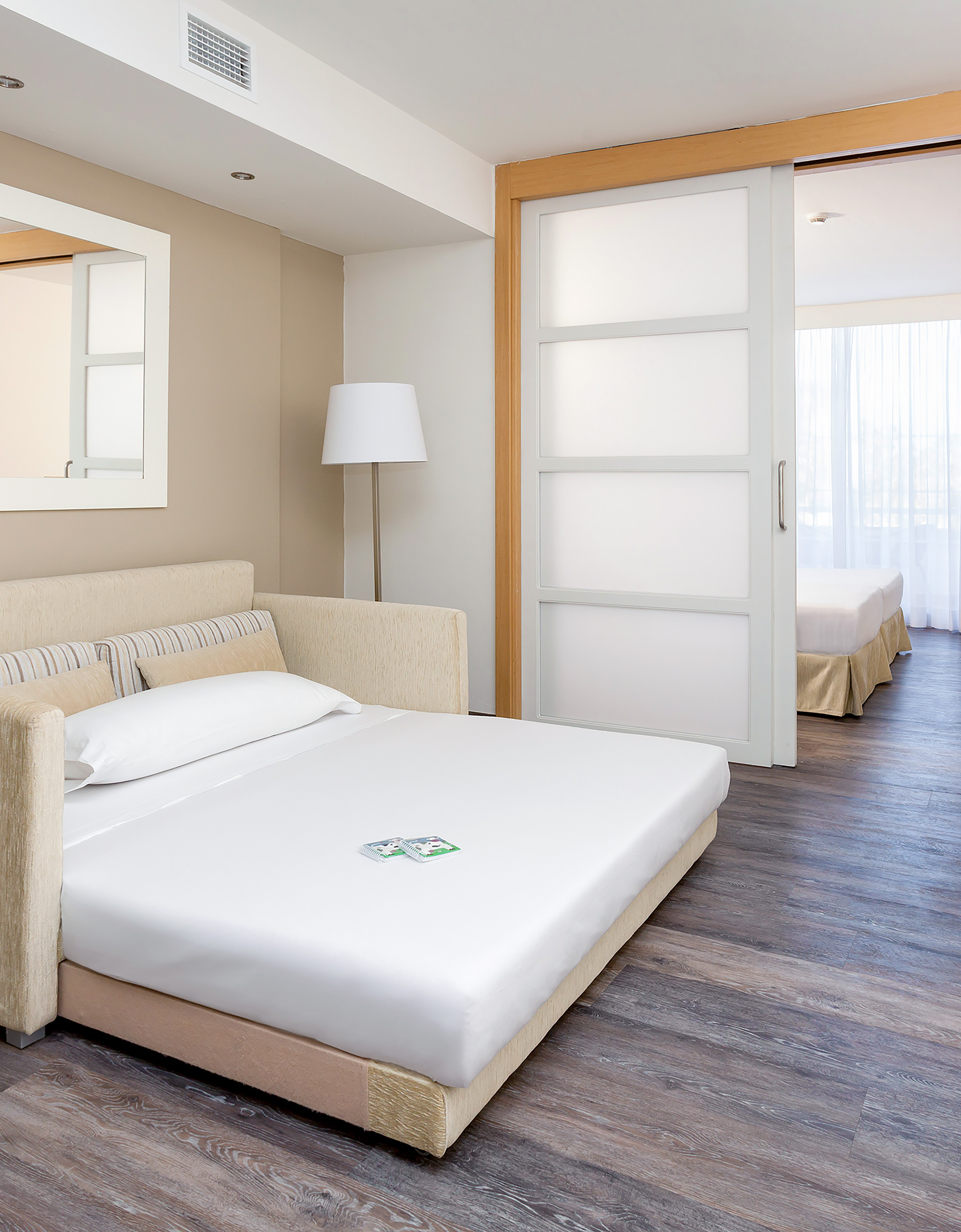 Modern studio with pull-out sofa bed, wood floor, and sliding bedroom door.