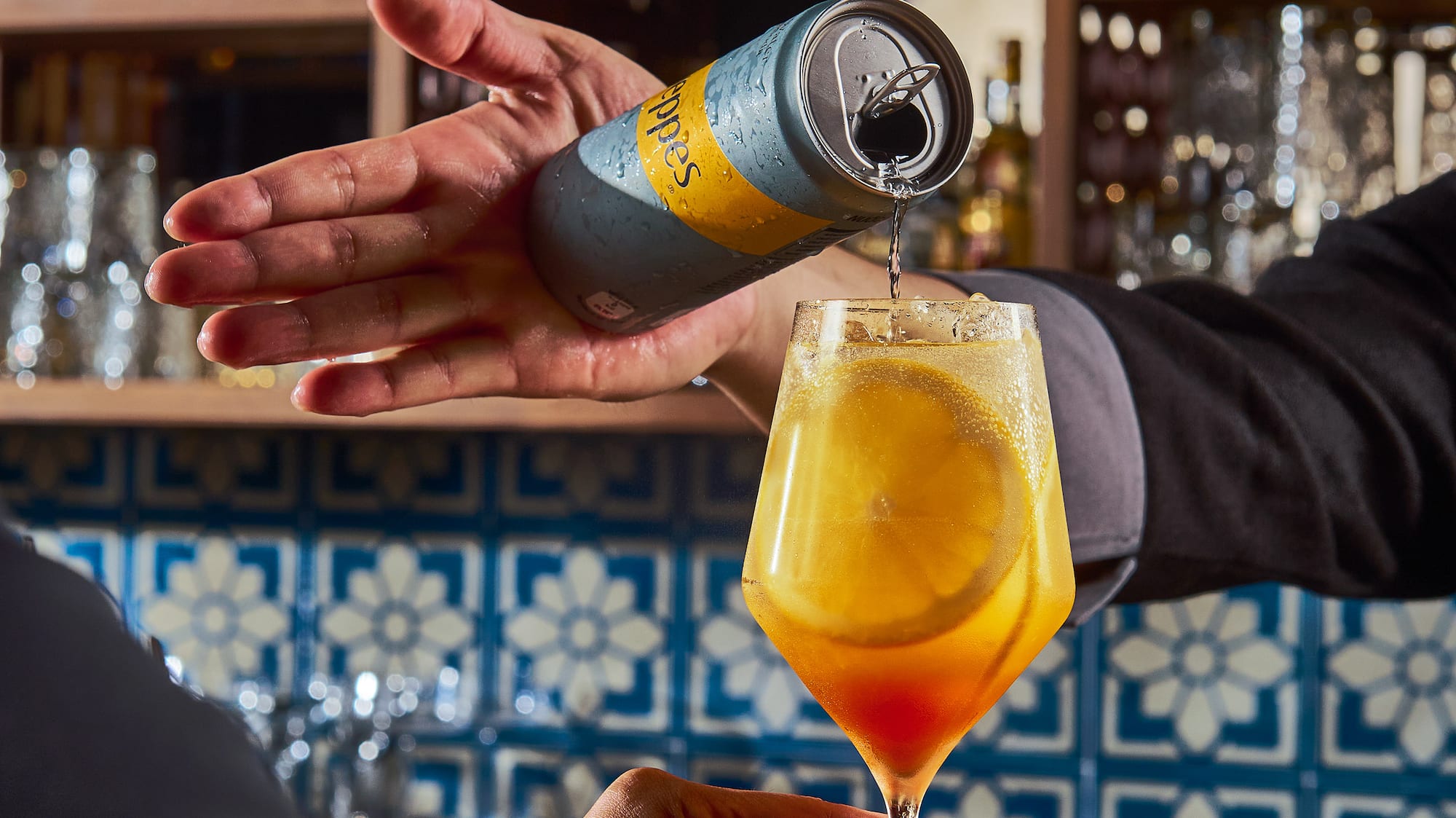 a person pouring a drink into a glass