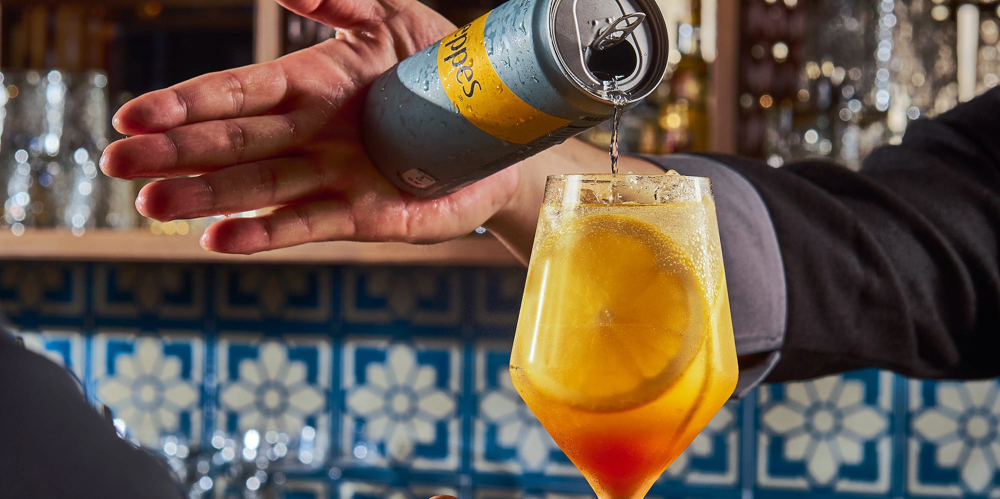 a person pouring a drink into a glass