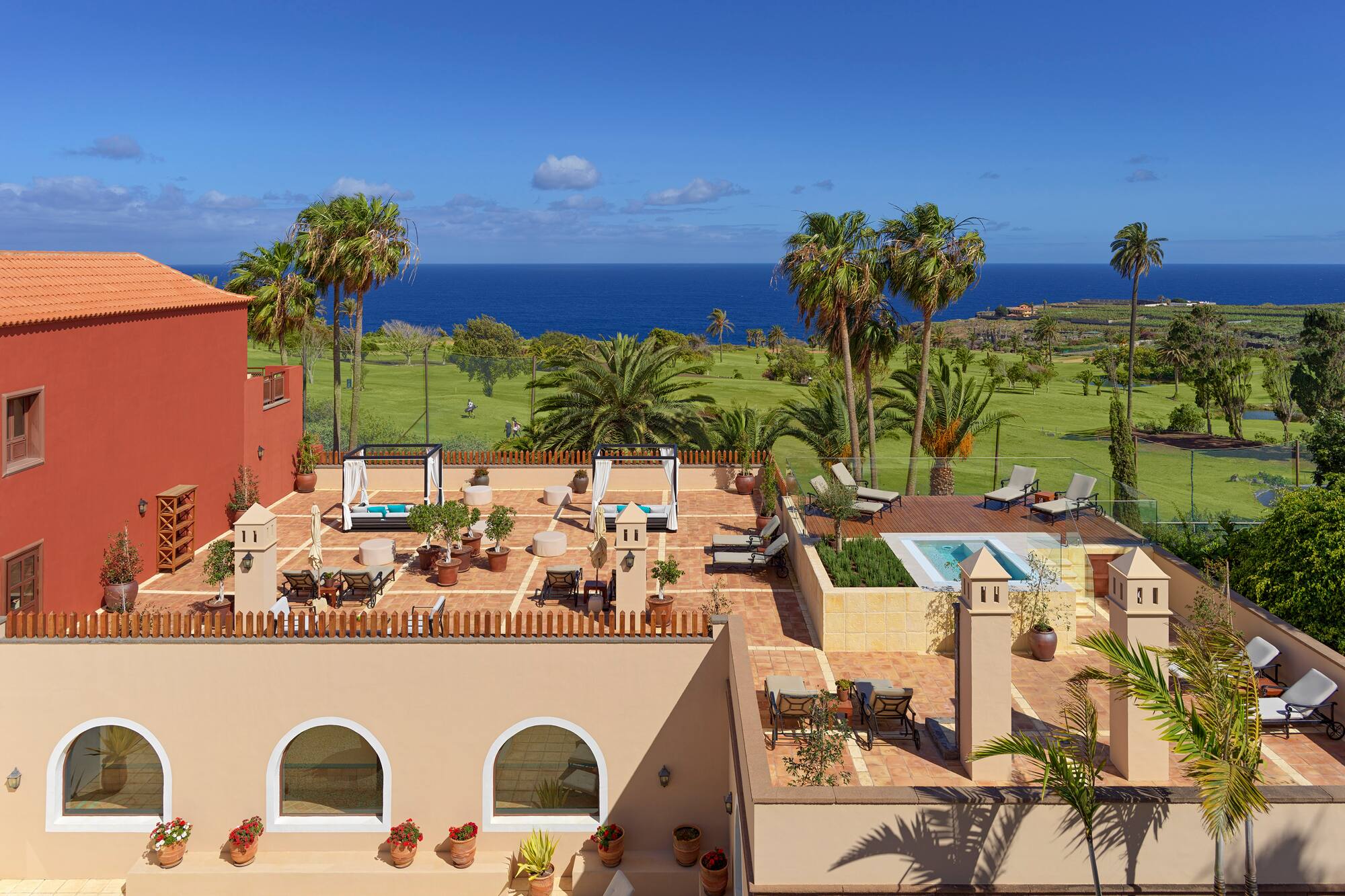 Luxury resort rooftop terrace, ocean view, golf course, palm trees.