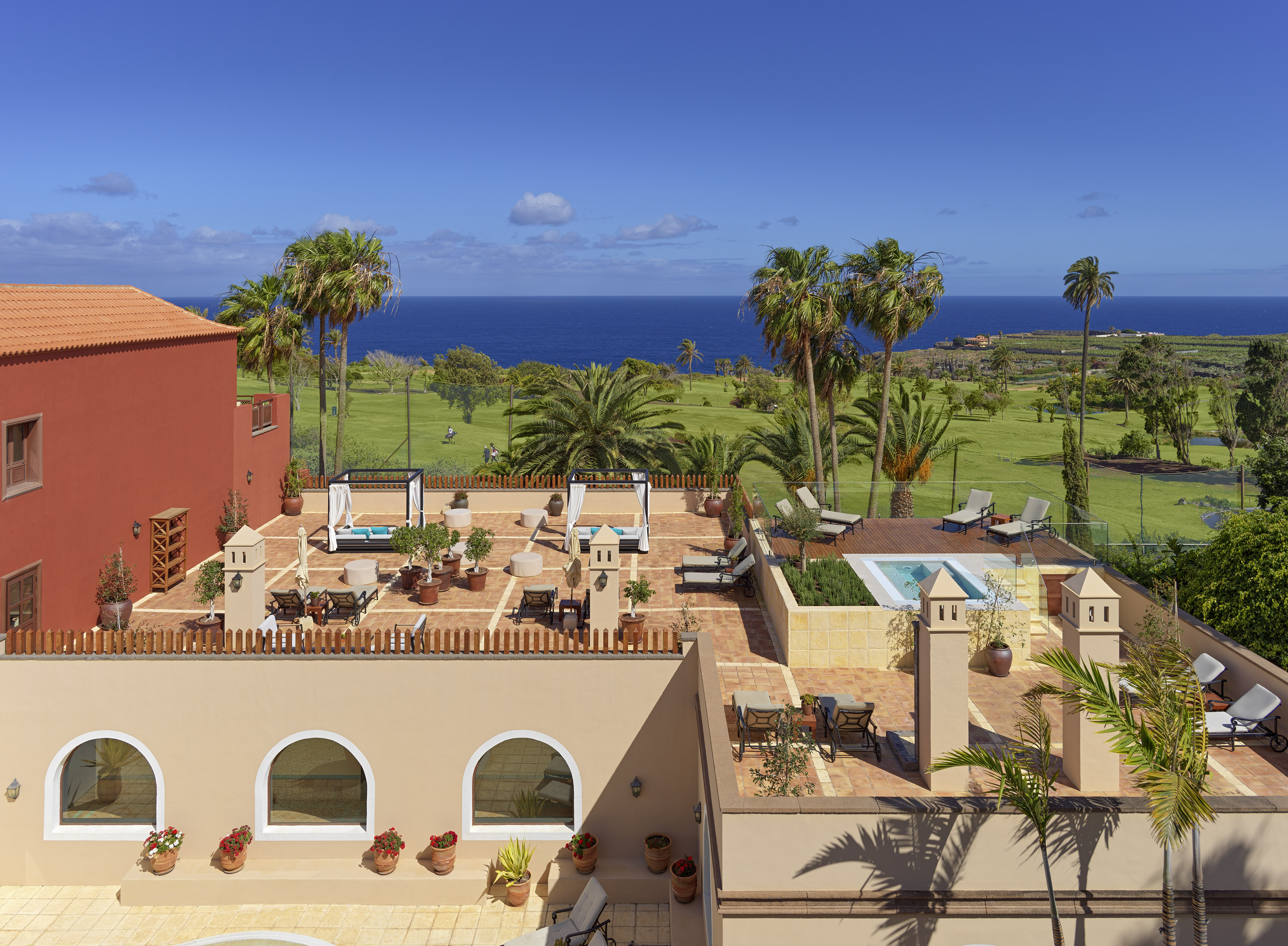 Luxury resort rooftop terrace, ocean view, golf course, palm trees.