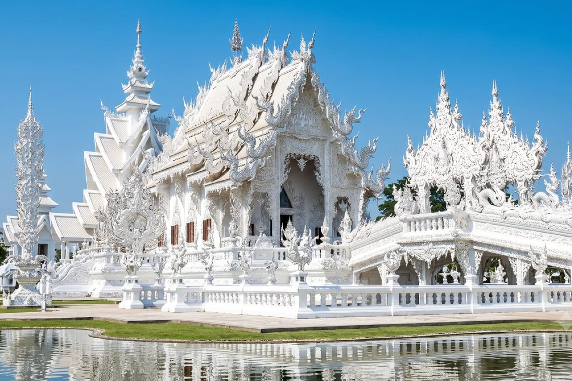 White Temple (Wat Rong Khun) in Thailand, ornate architecture reflecting in water.