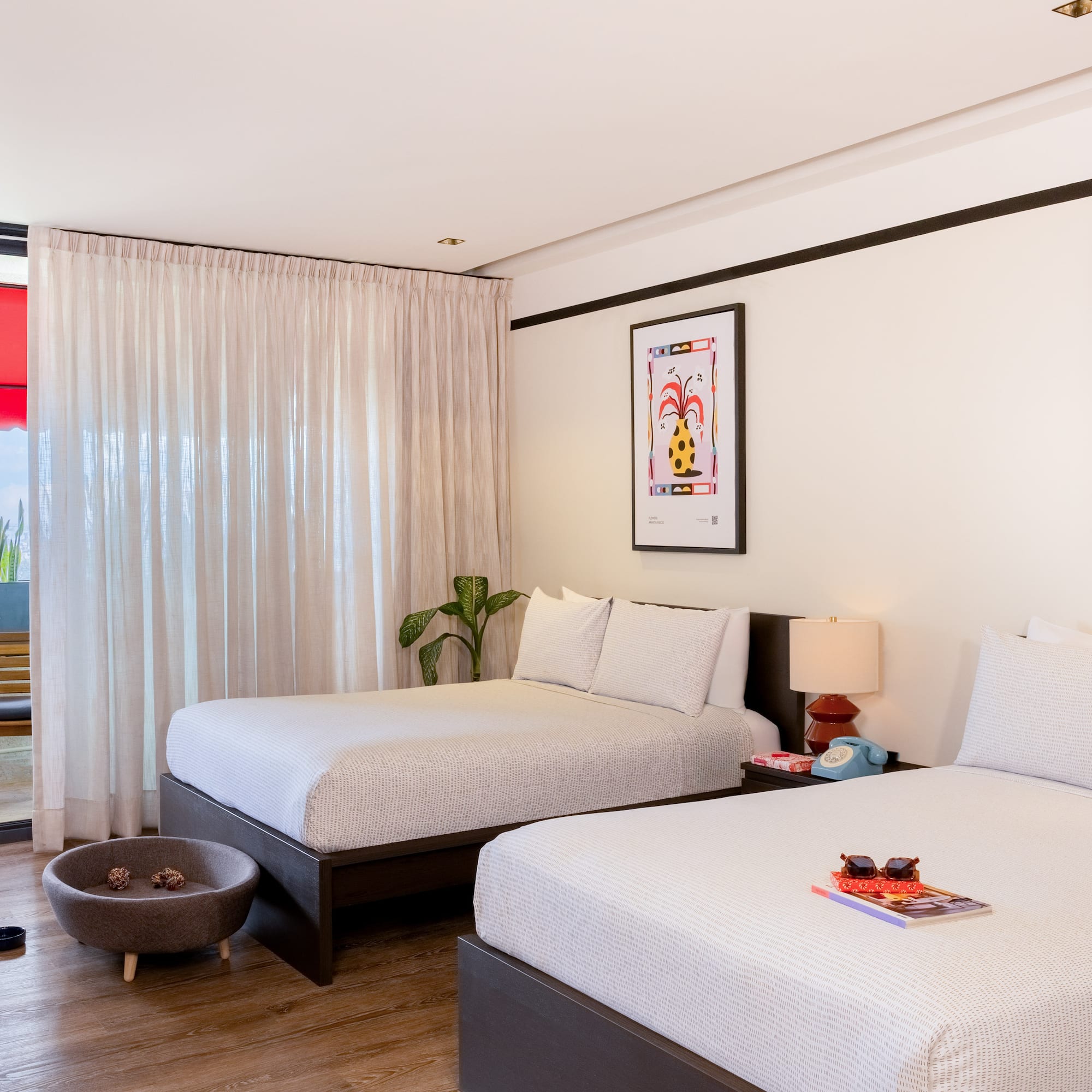 Pet-friendly hotel room with two beds, modern decor, artwork, and balcony.