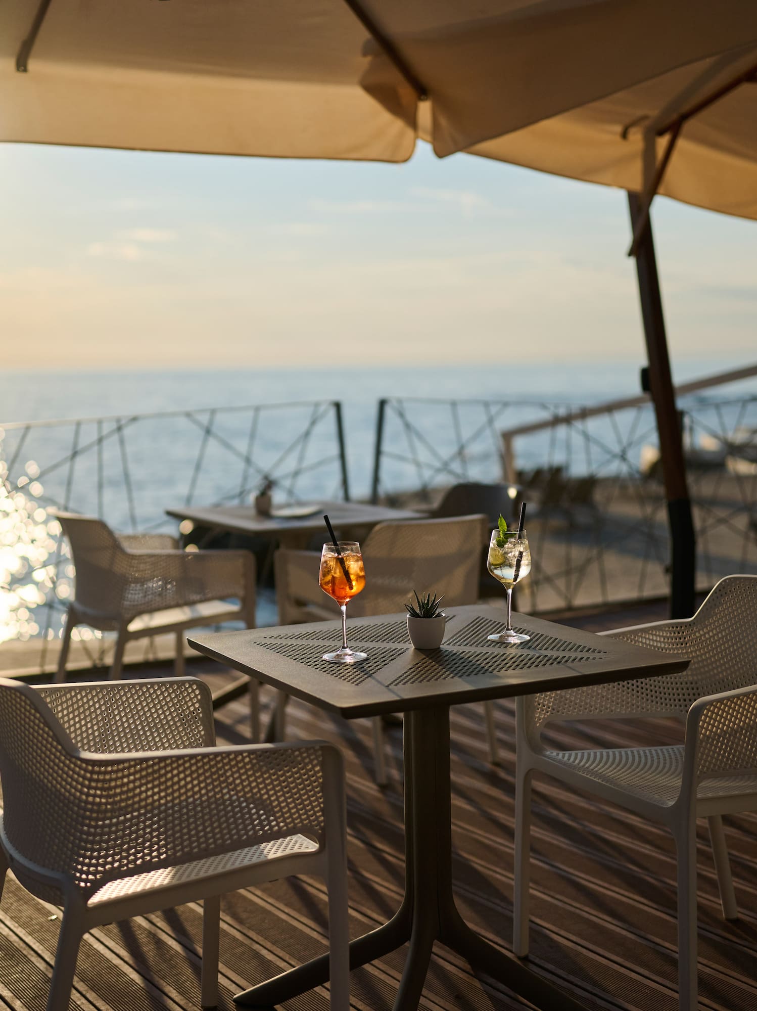 a table and chairs on a deck with a view of the ocean