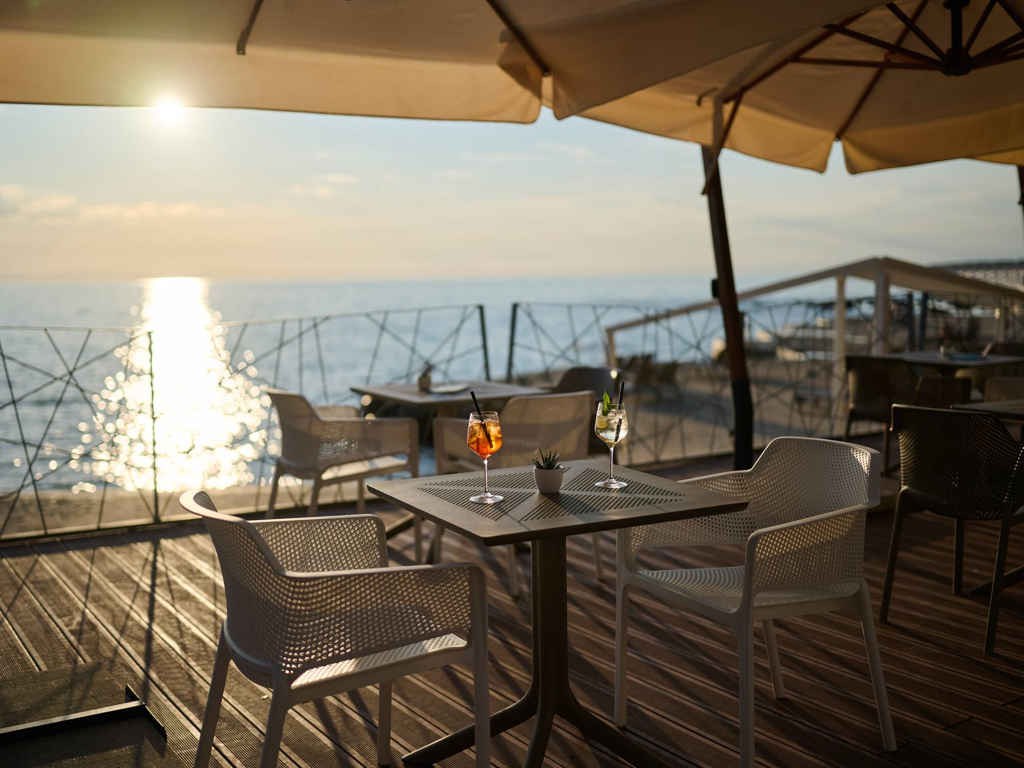 a table and chairs on a deck with a view of the ocean