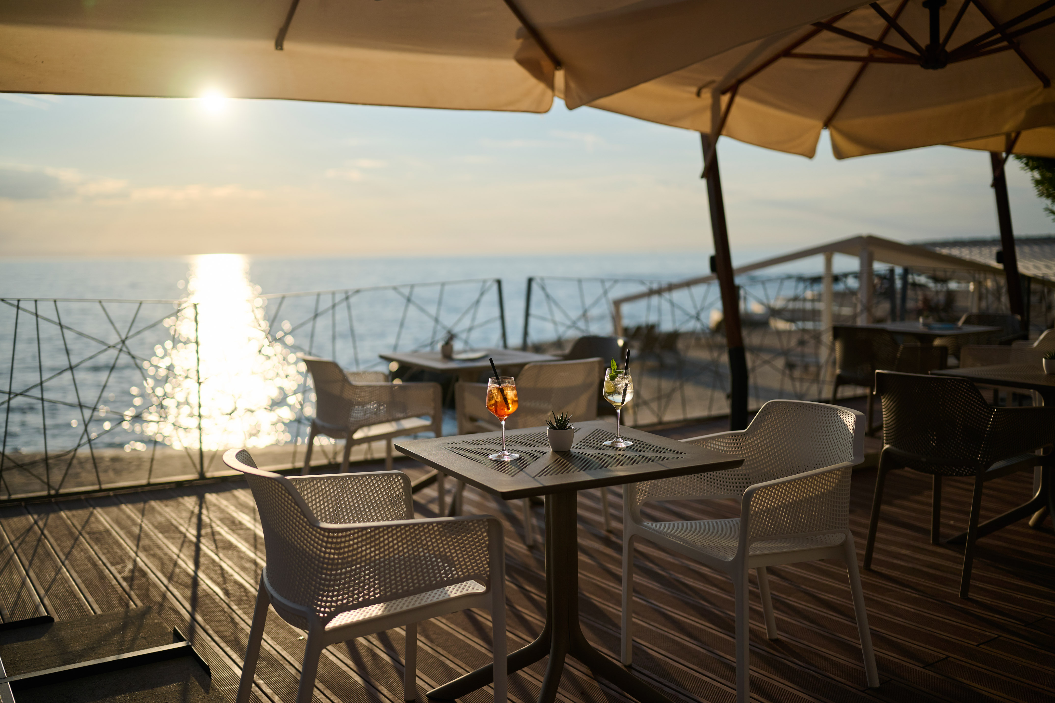 a table and chairs on a deck with a view of the ocean