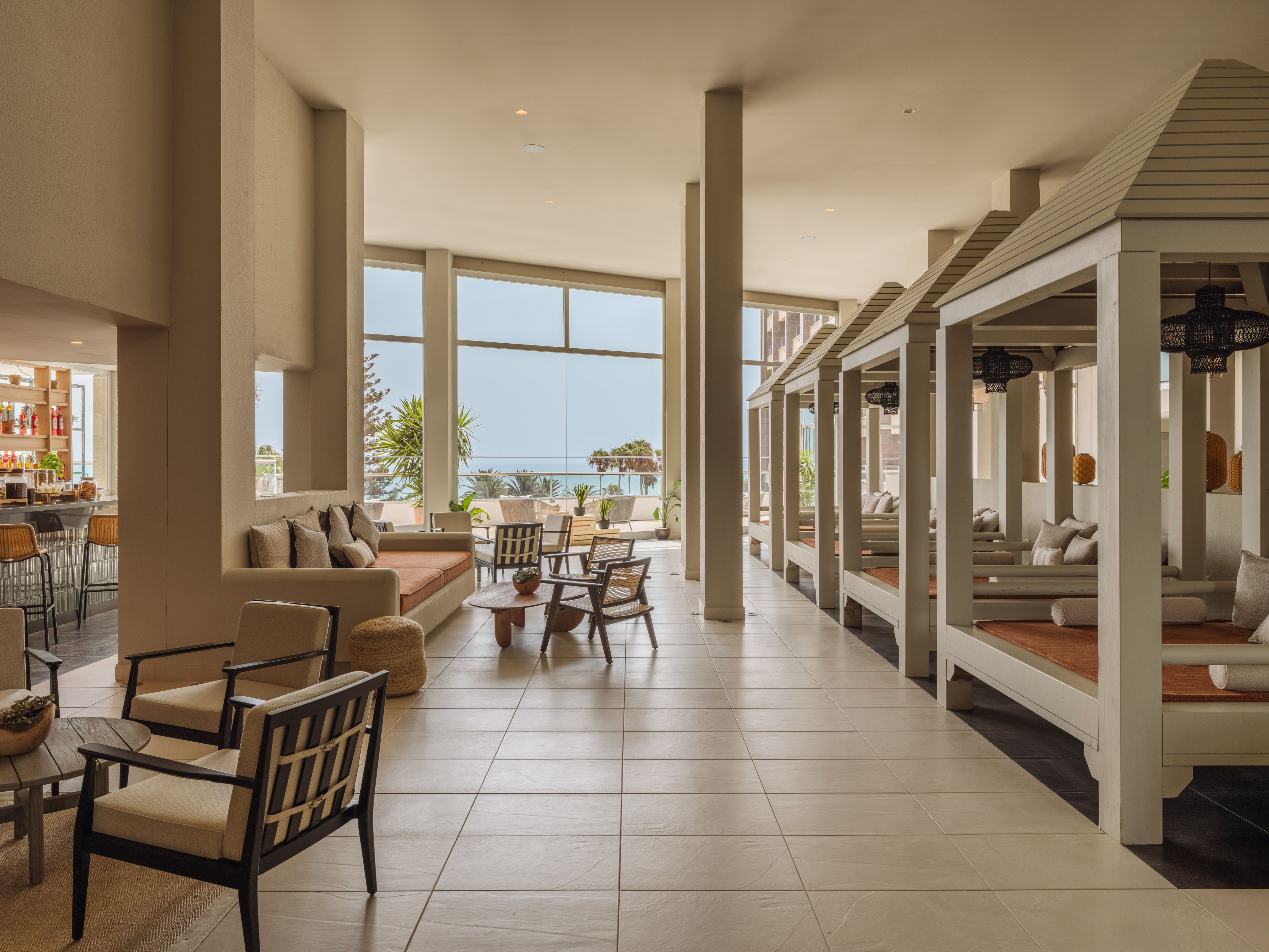 Spacious hotel lounge with ocean view, modern seating, and indoor daybeds.