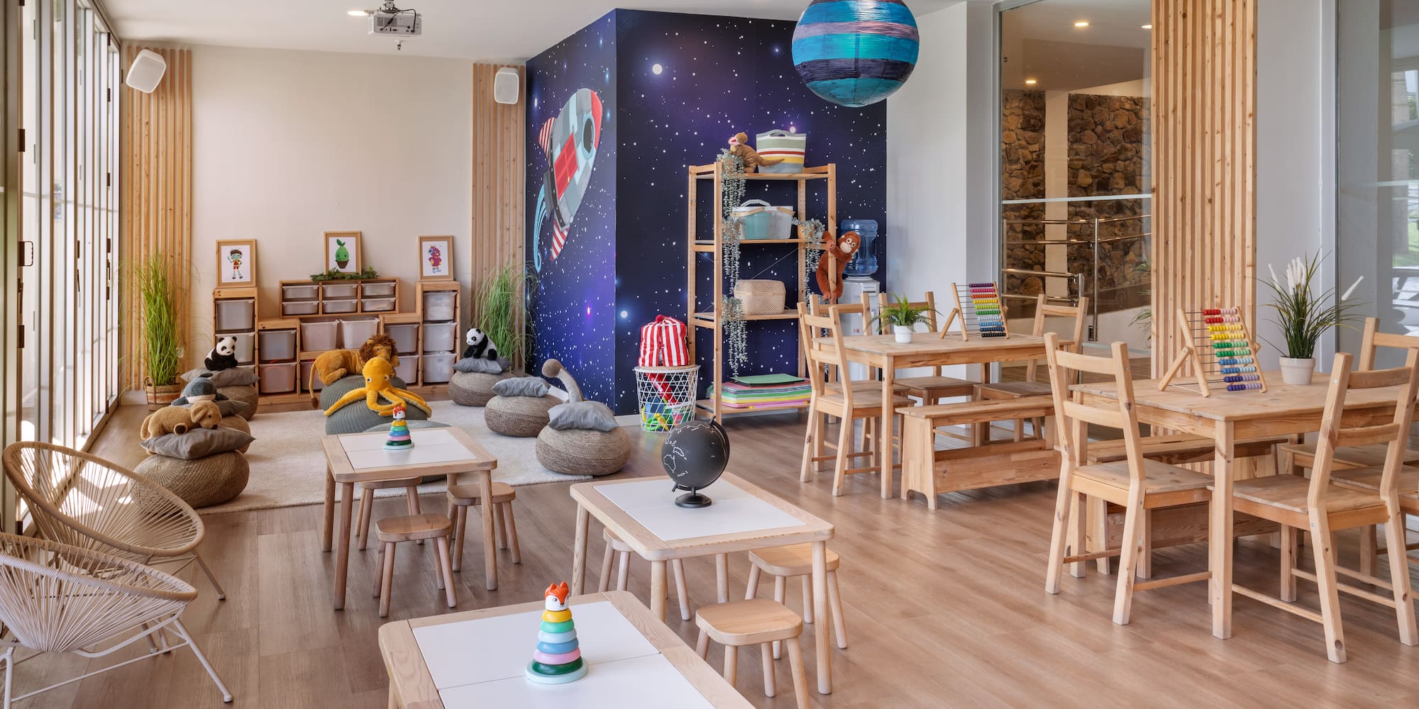 Colorful children's play area, space theme mural, wooden tables, and toys.