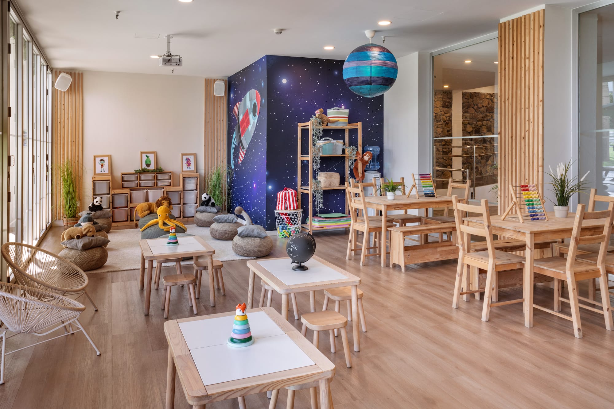 Colorful children's play area, space theme mural, wooden tables, and toys.