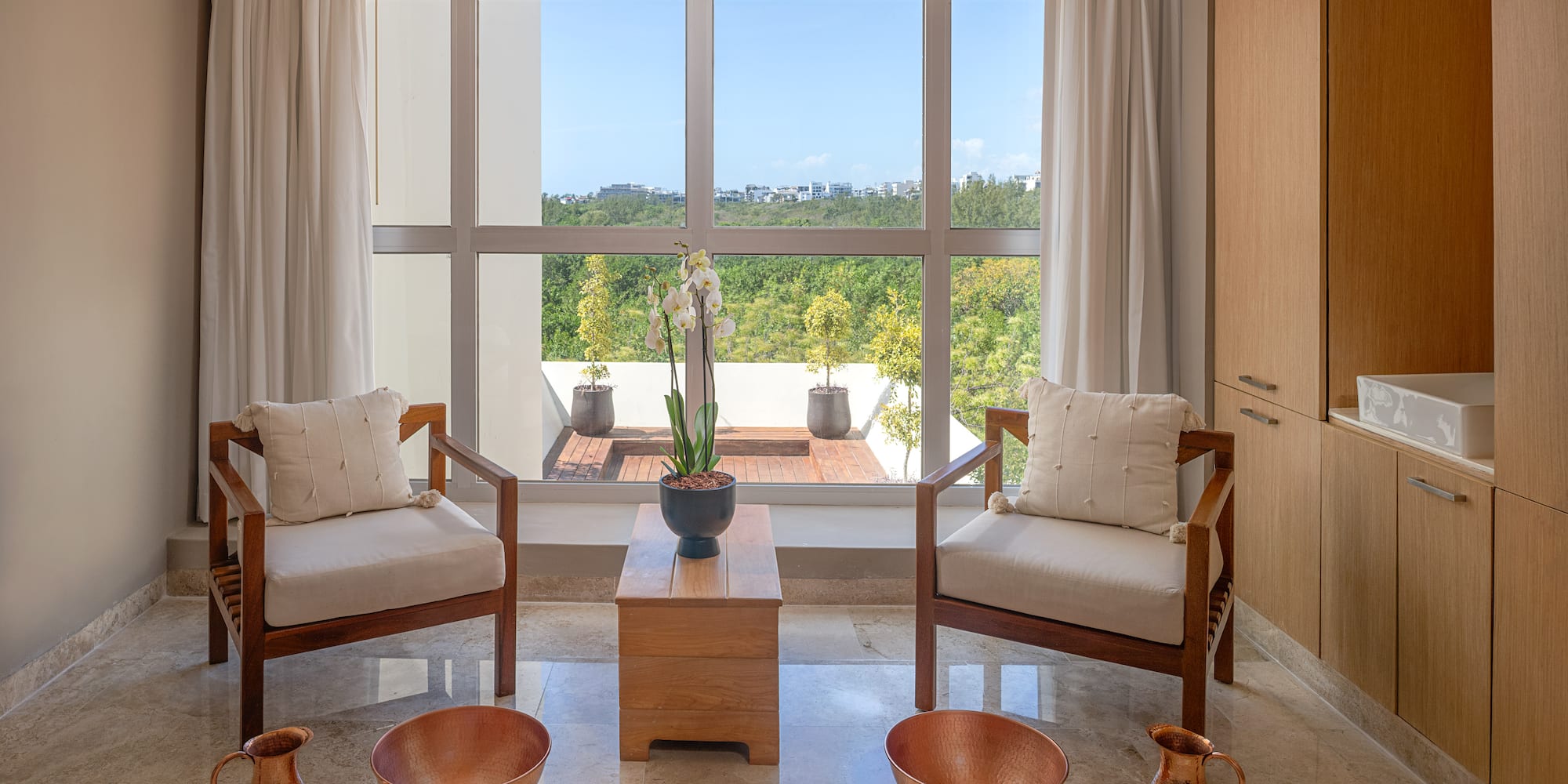 Serene spa room with foot soak bowls, two chairs, and a window view.