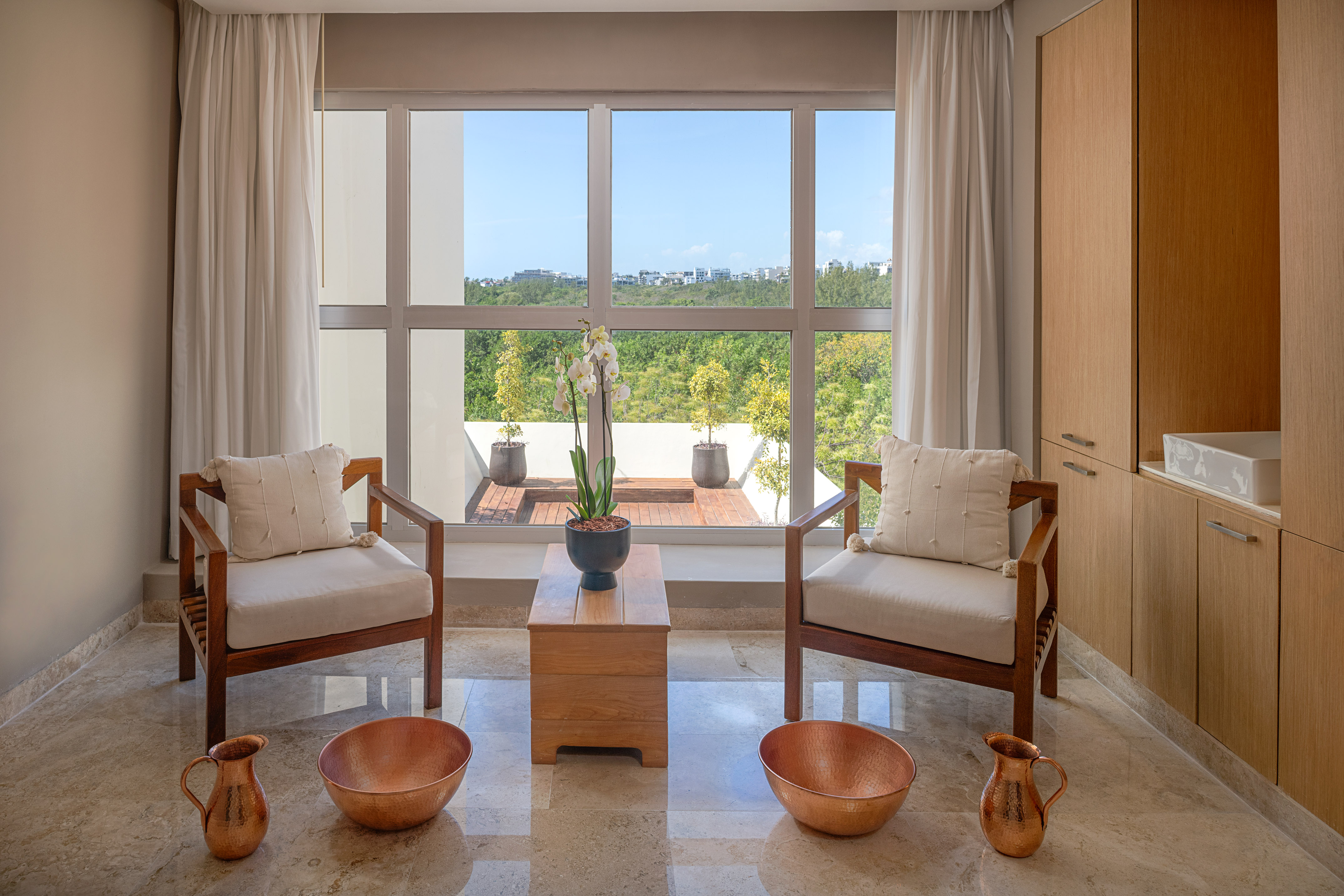 Serene spa room with foot soak bowls, two chairs, and a window view.