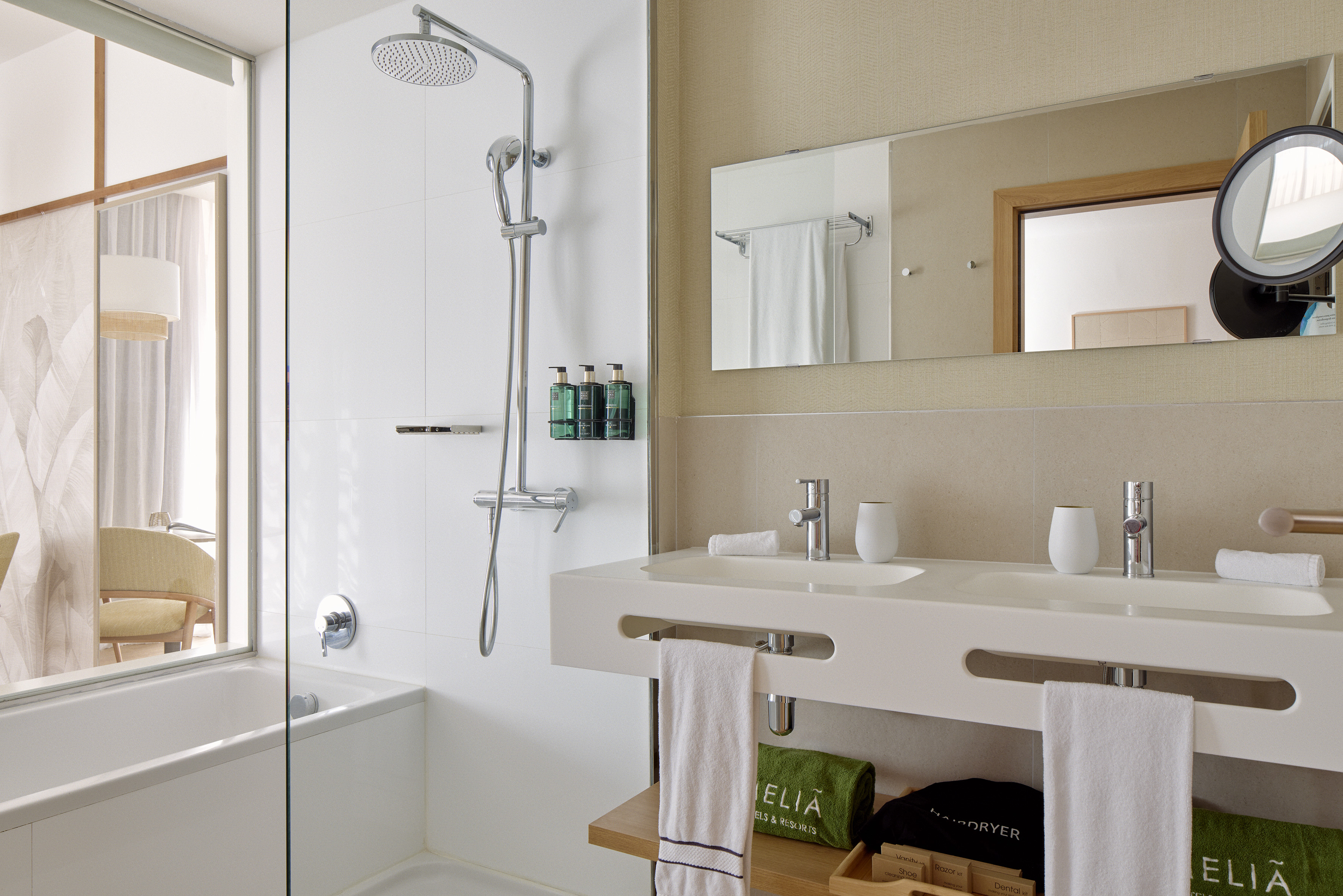 Modern hotel bathroom with rain shower, bathtub, and floating double vanity.