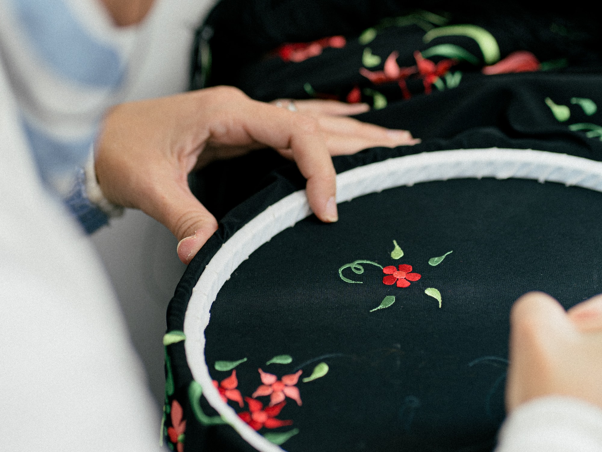 a person sewing a black fabric with a red flower on it