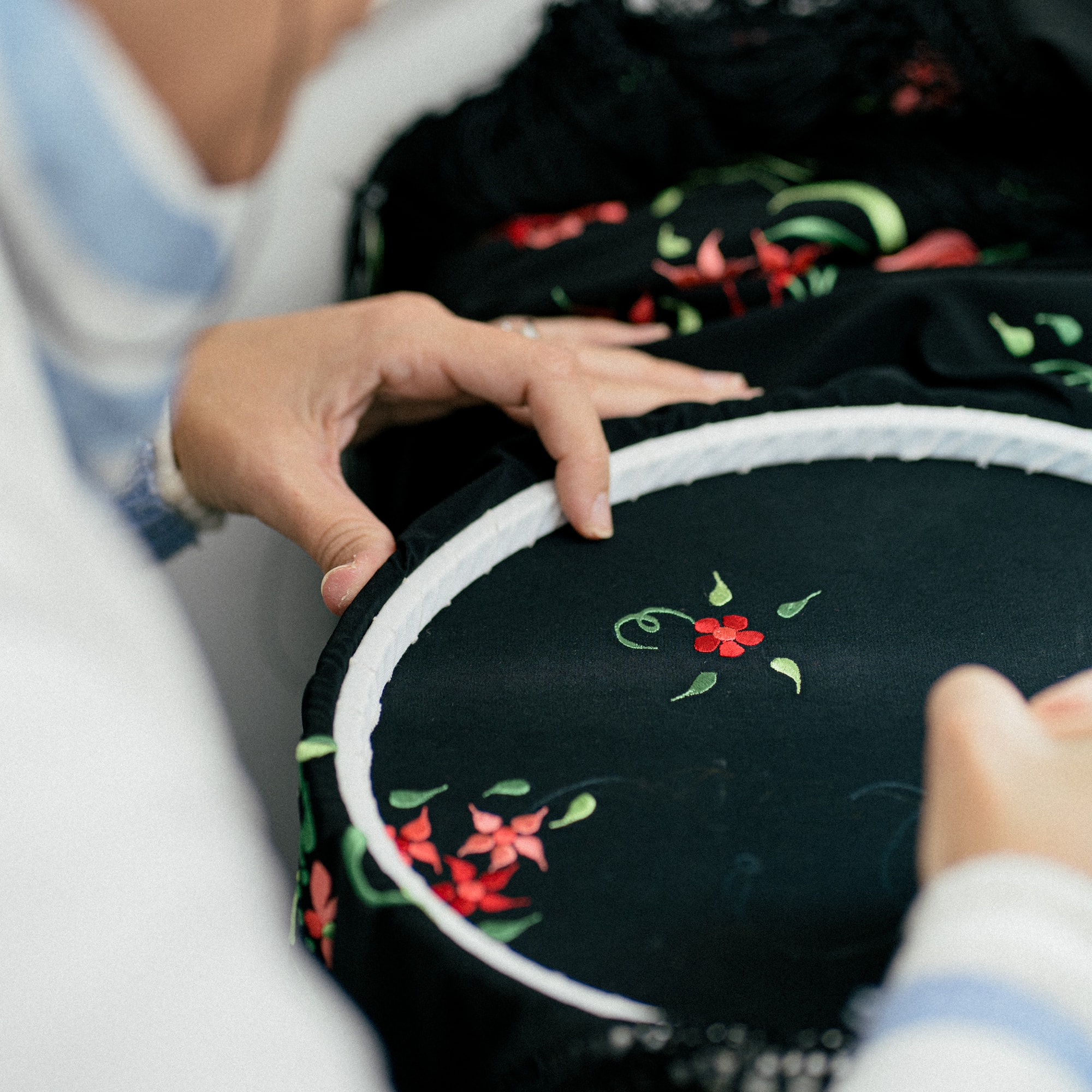a person sewing a black fabric with a red flower on it