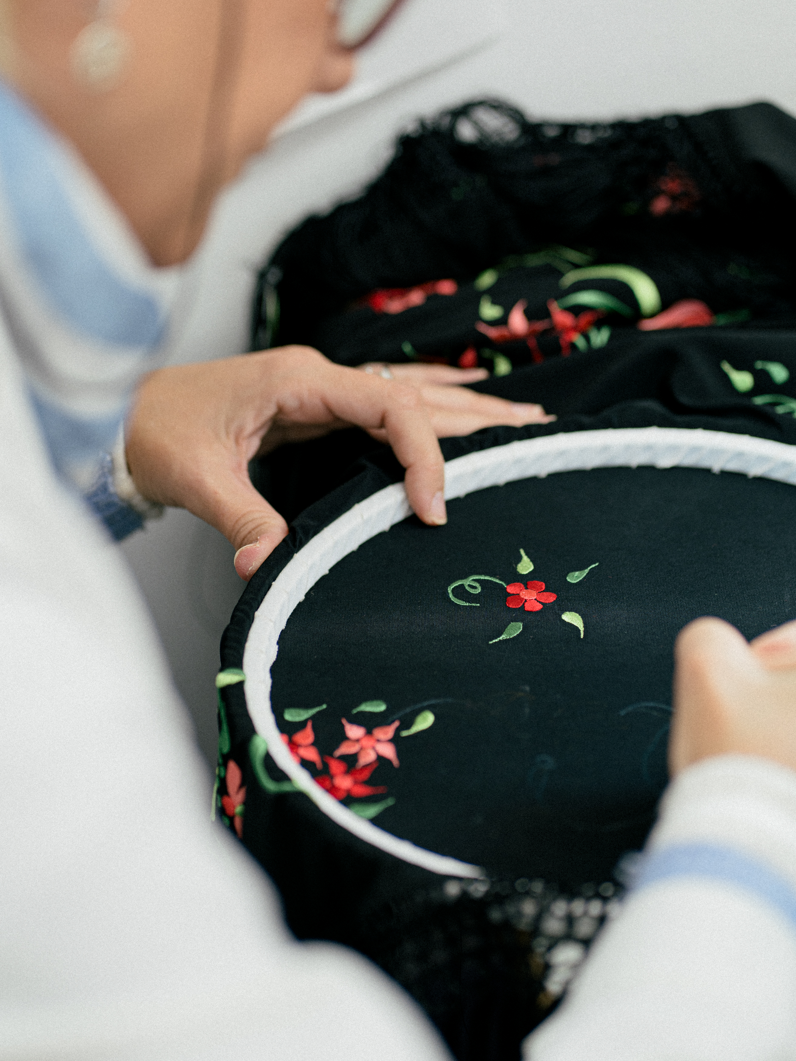 a person sewing a black fabric with a red flower on it