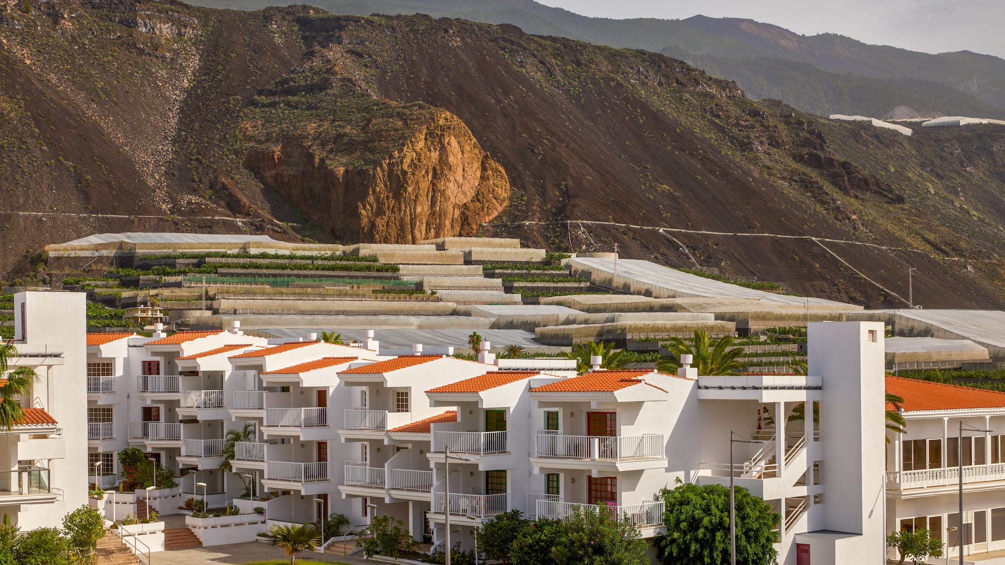a white building with orange roofs and a hill in the background