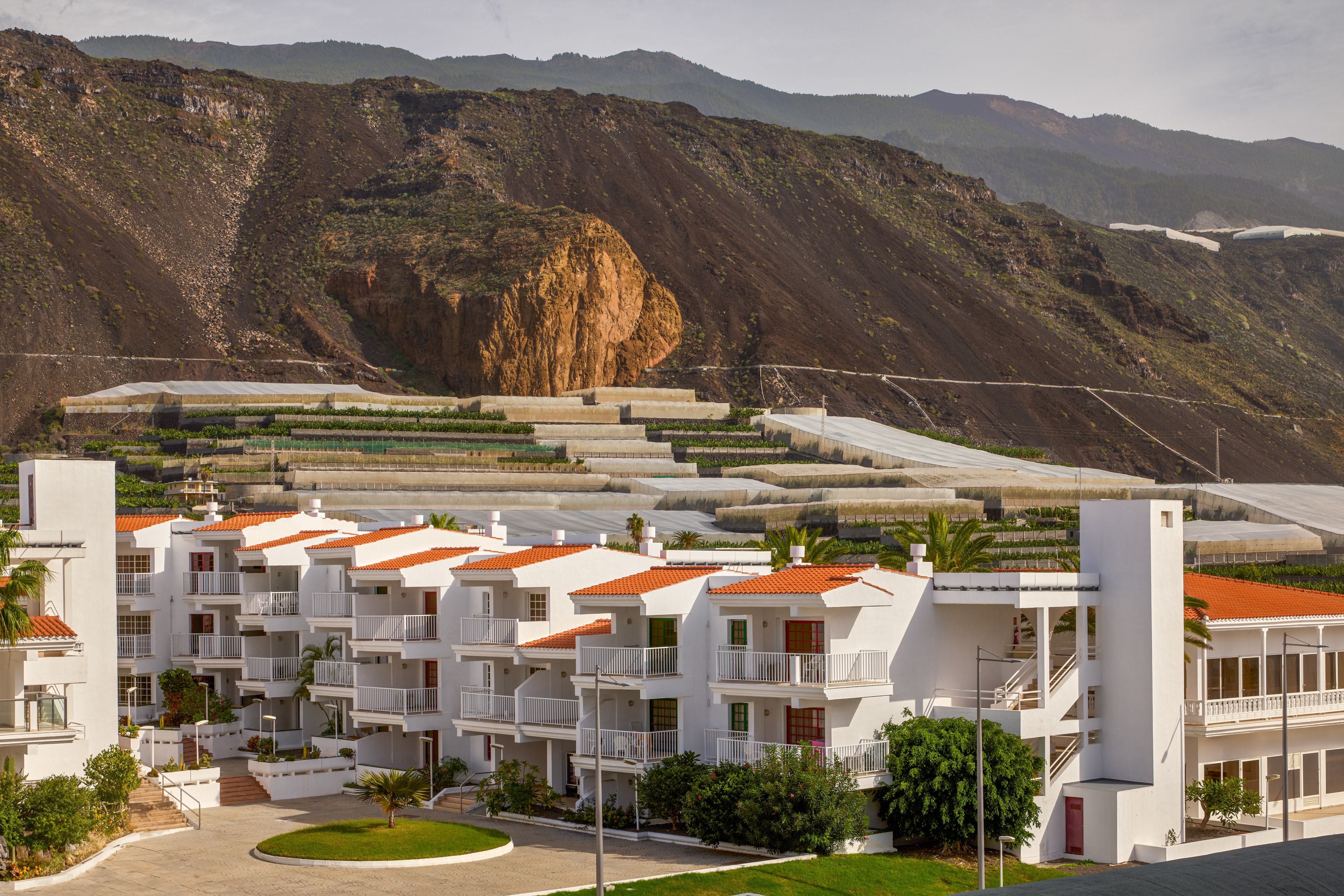 White buildings, red roofs, terraced banana plantations, volcanic mountain.