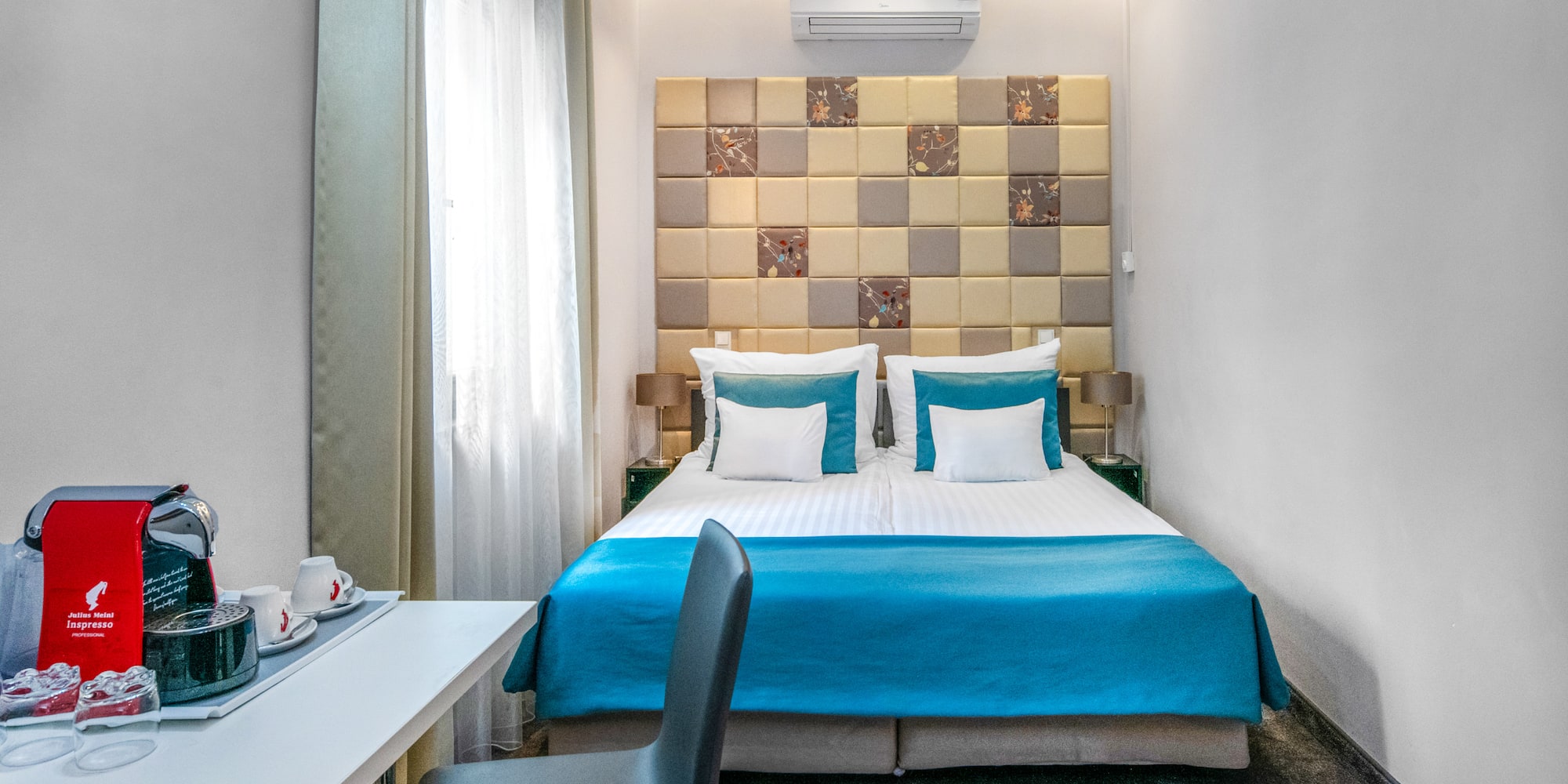 a bed with blue sheets and a desk in a room