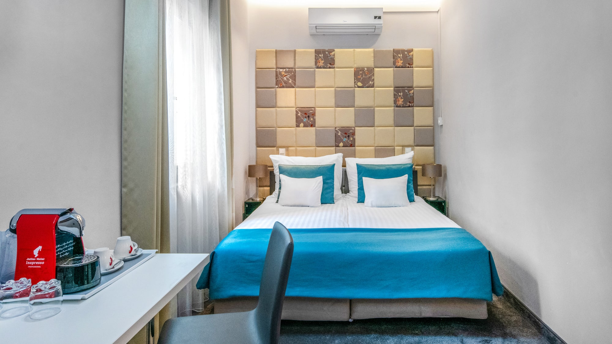 a bed with blue sheets and a desk in a room