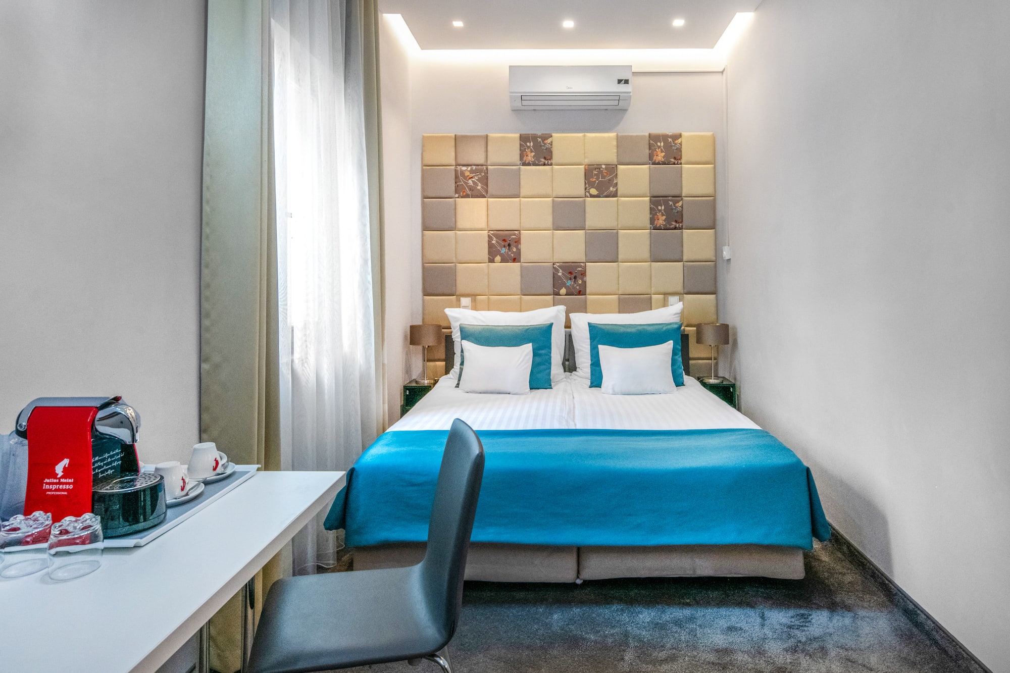 a bed with blue sheets and a desk in a room