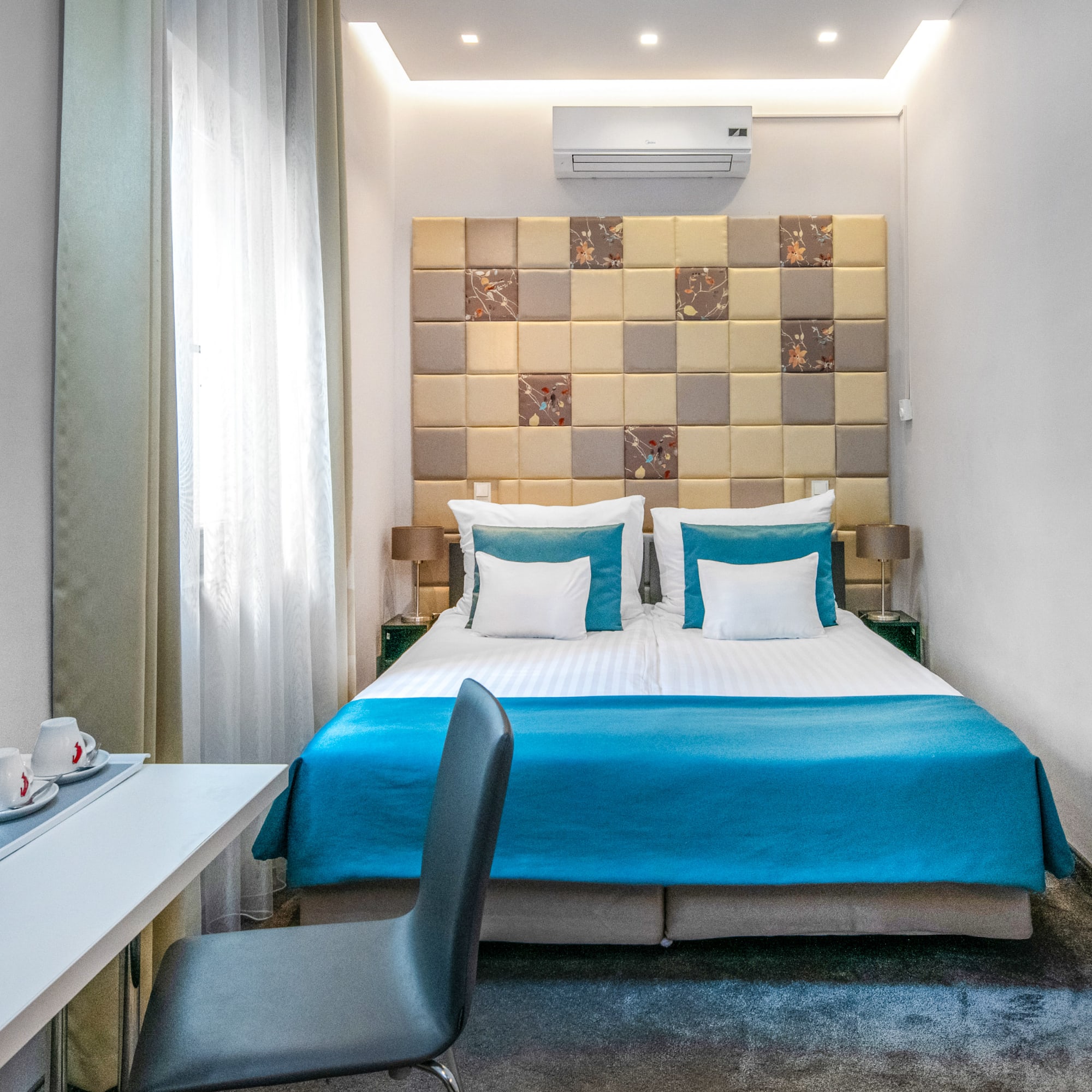 a bed with blue sheets and a desk in a room