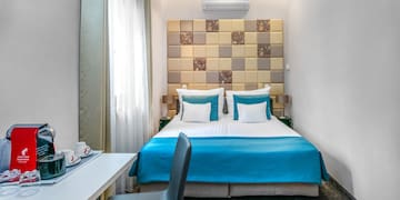 a bed with blue sheets and a desk in a room