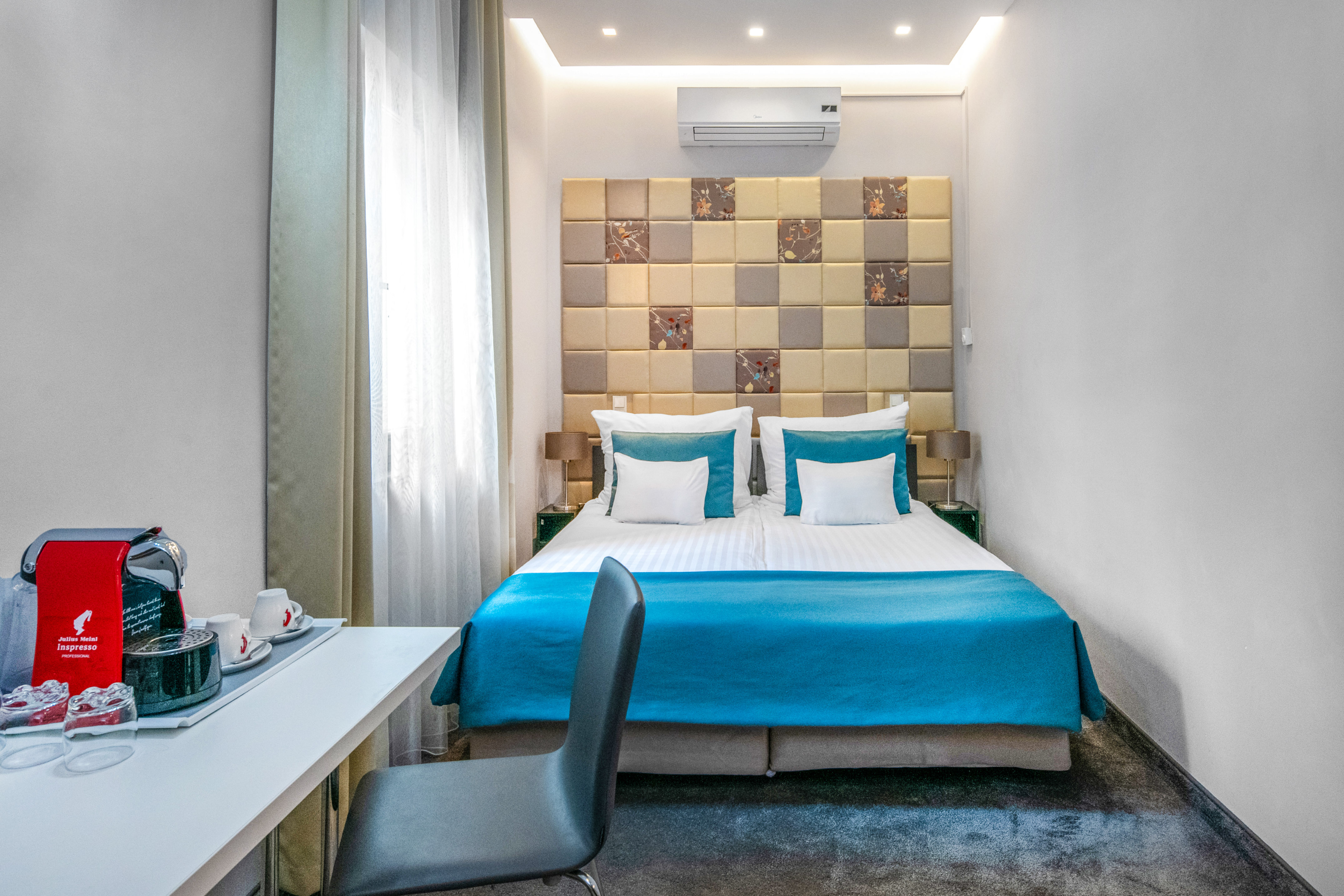 a bed with blue sheets and a desk in a room