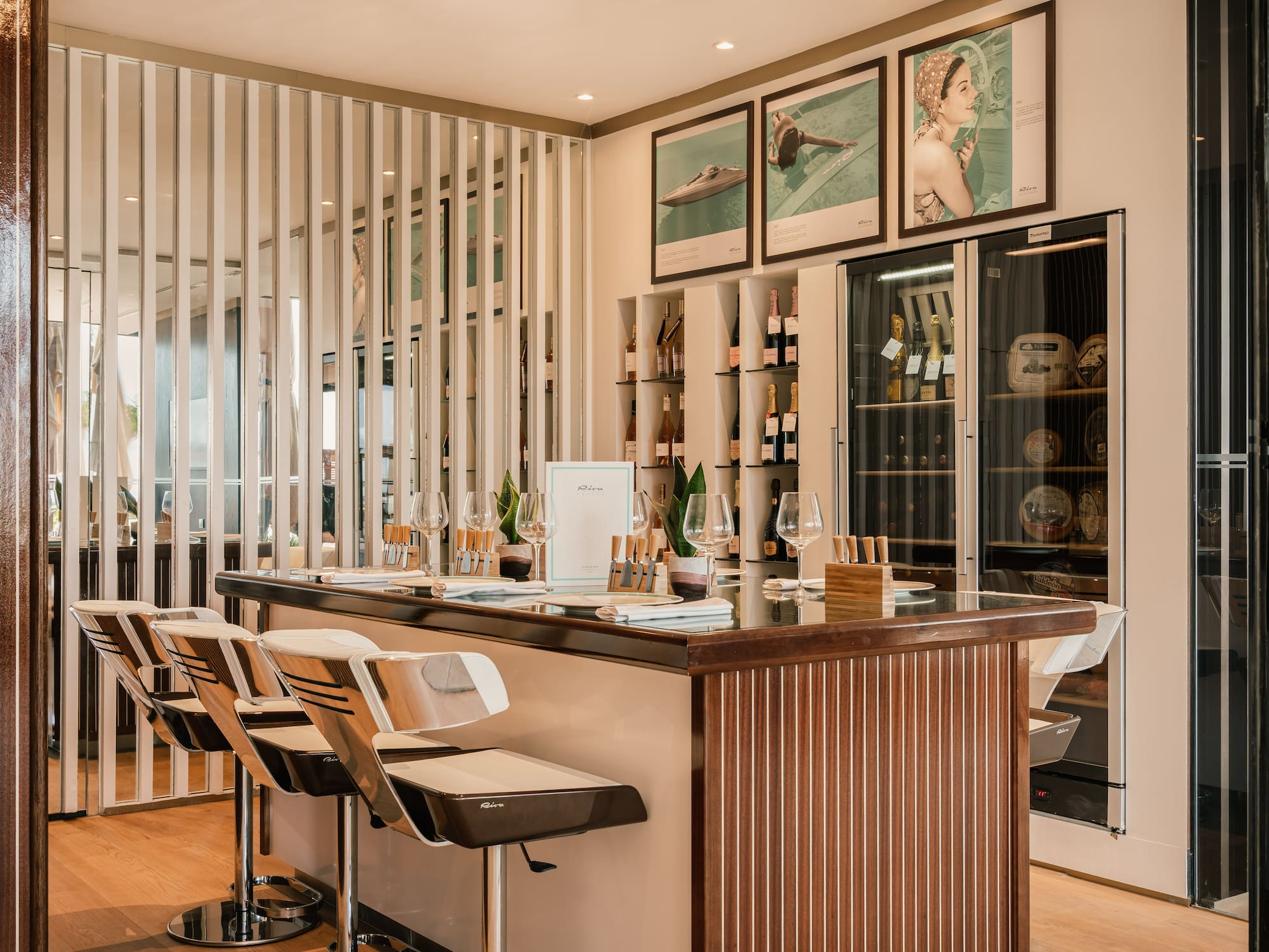 a bar with chairs and a shelf with wine bottles