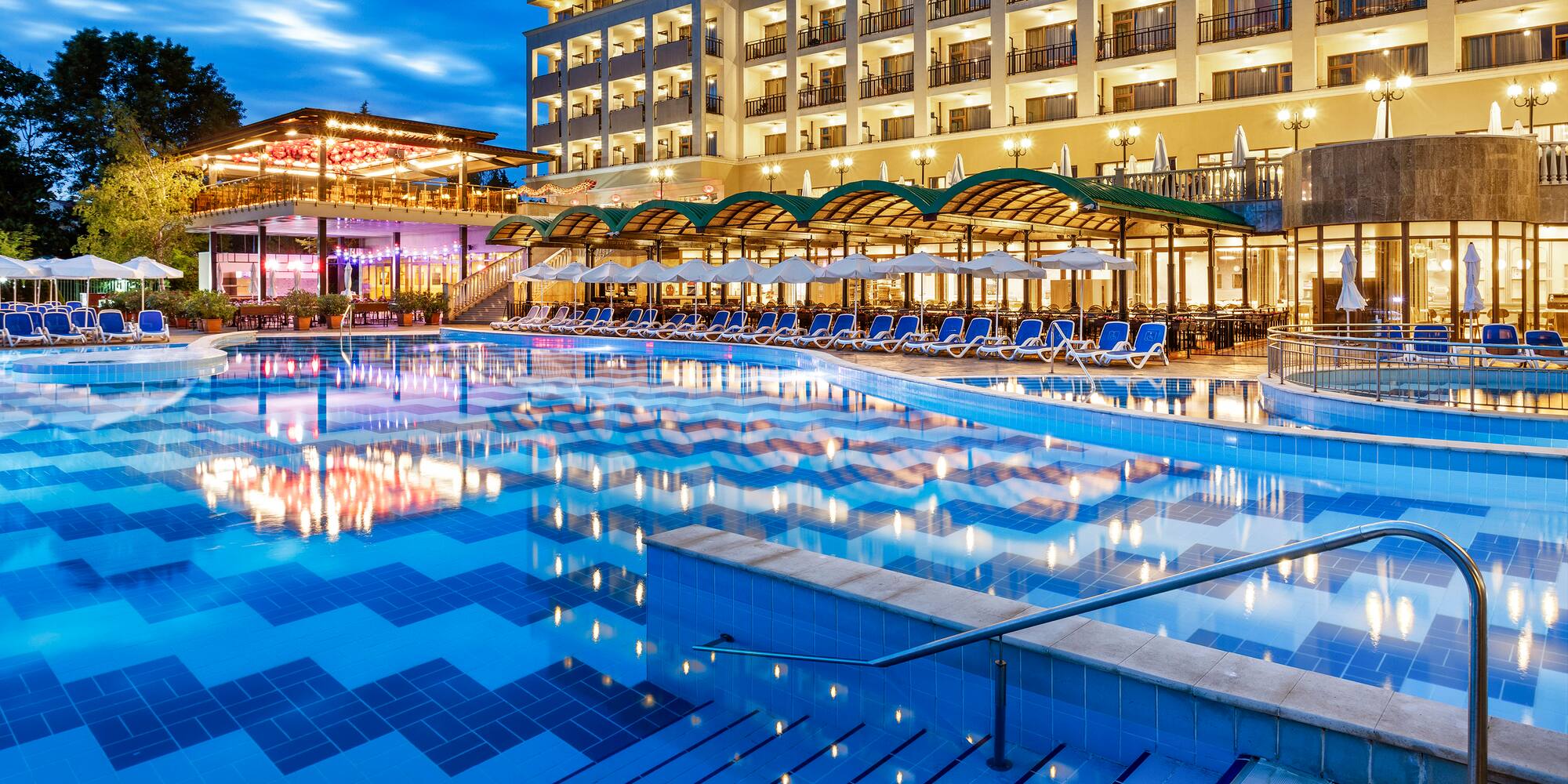 a pool with chairs and a building in the background