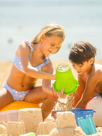 a boy and girl playing with sand on a beach