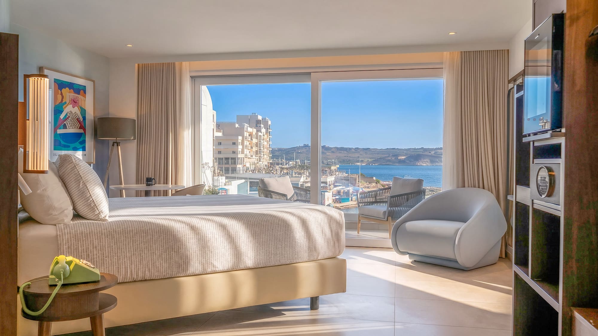 Bright bedroom with panoramic bay view, large bed, and modern seating.