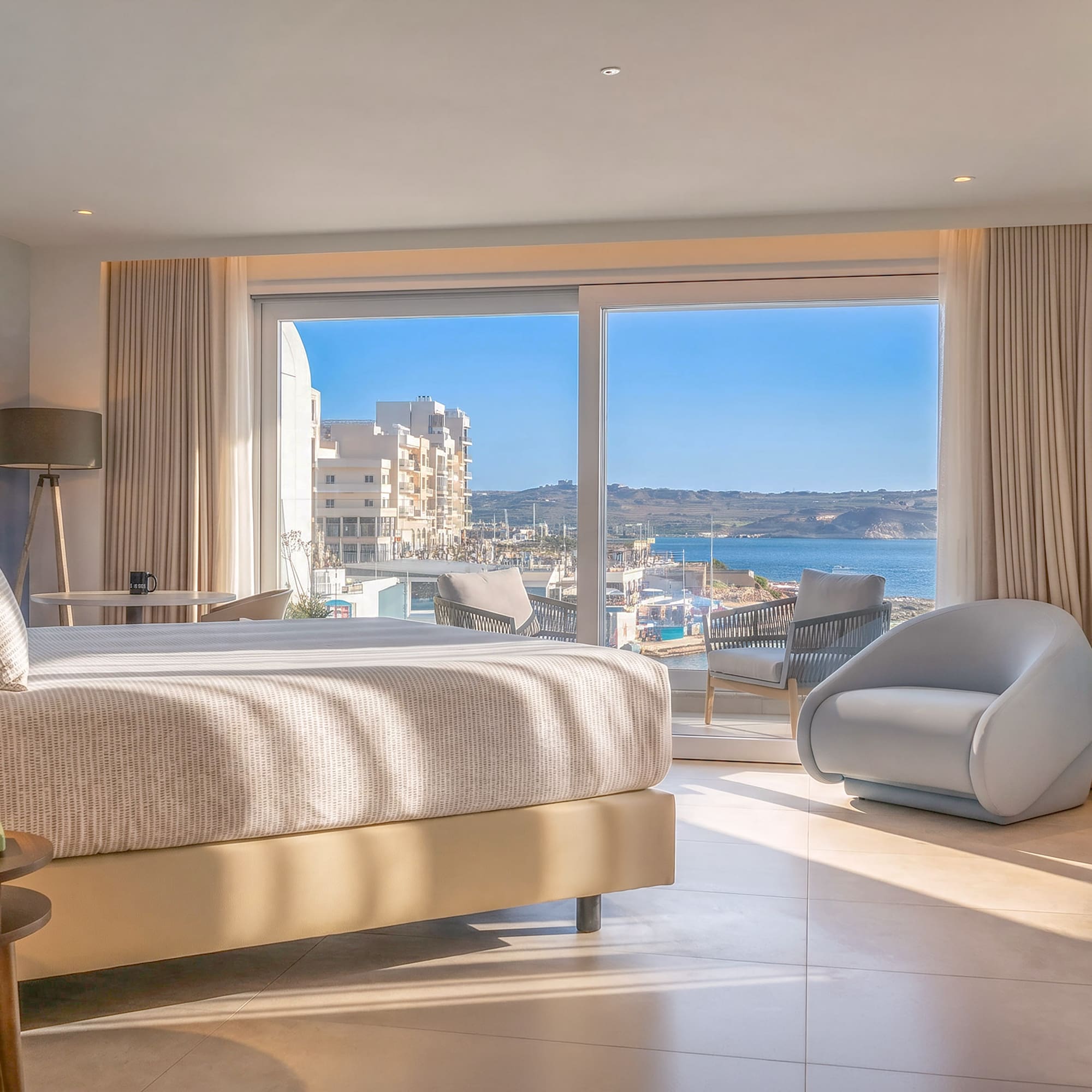 Modern hotel room with bed, balcony, and sea view overlooking a marina.