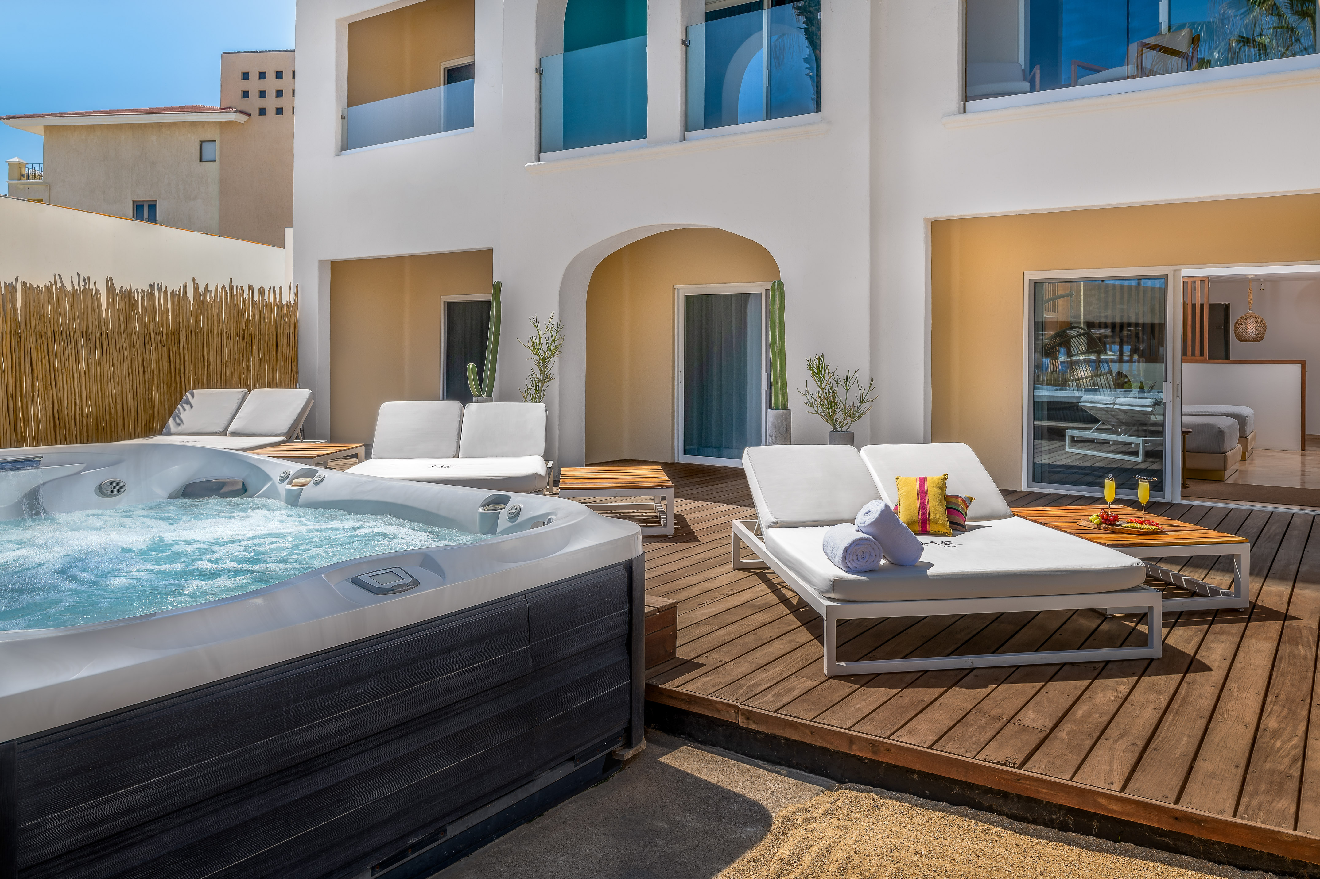 Luxury resort patio with bubbling hot tub, wooden deck, and lounge chairs.