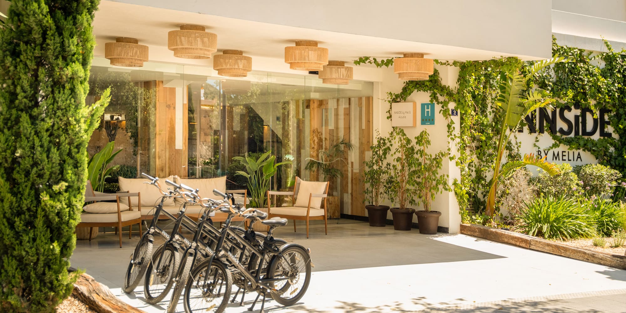INNSiDE by Melia hotel entrance with bicycles, abundant greenery, and modern design.
