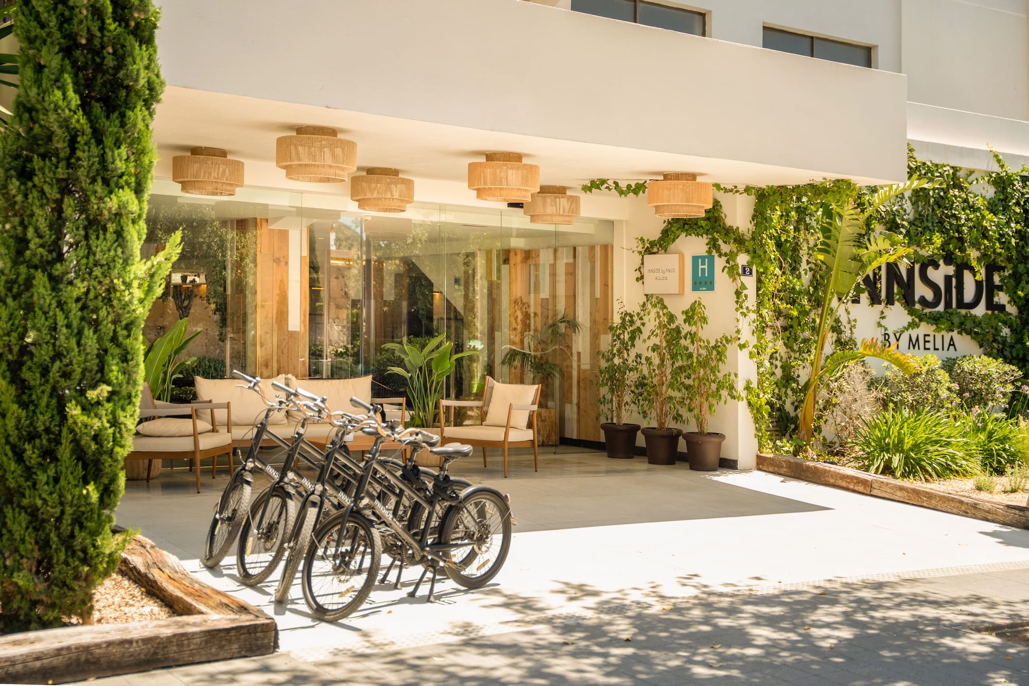 INNSiDE by Melia hotel entrance with bicycles, abundant greenery, and modern design.