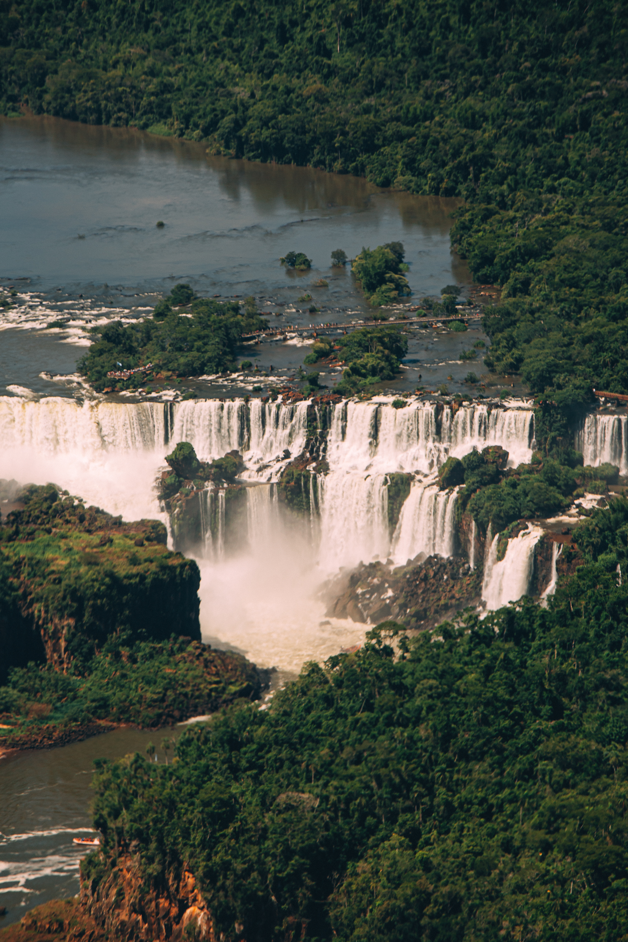 Aerial view of Iguazu Falls, powerful cascades, and lush green rainforest.