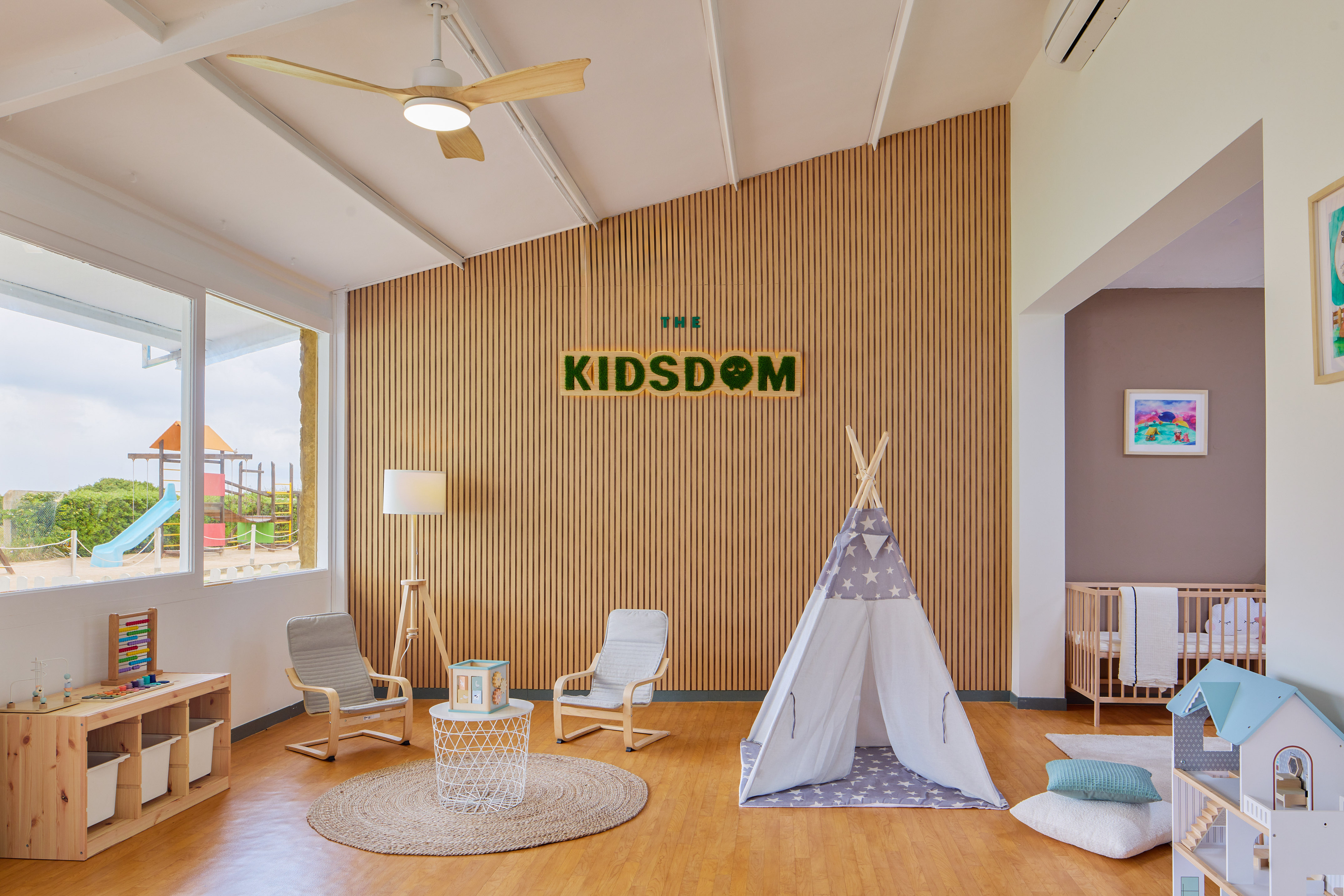 THE KIDSDOM kids playroom with teepee, toys, crib, and outdoor playground.
