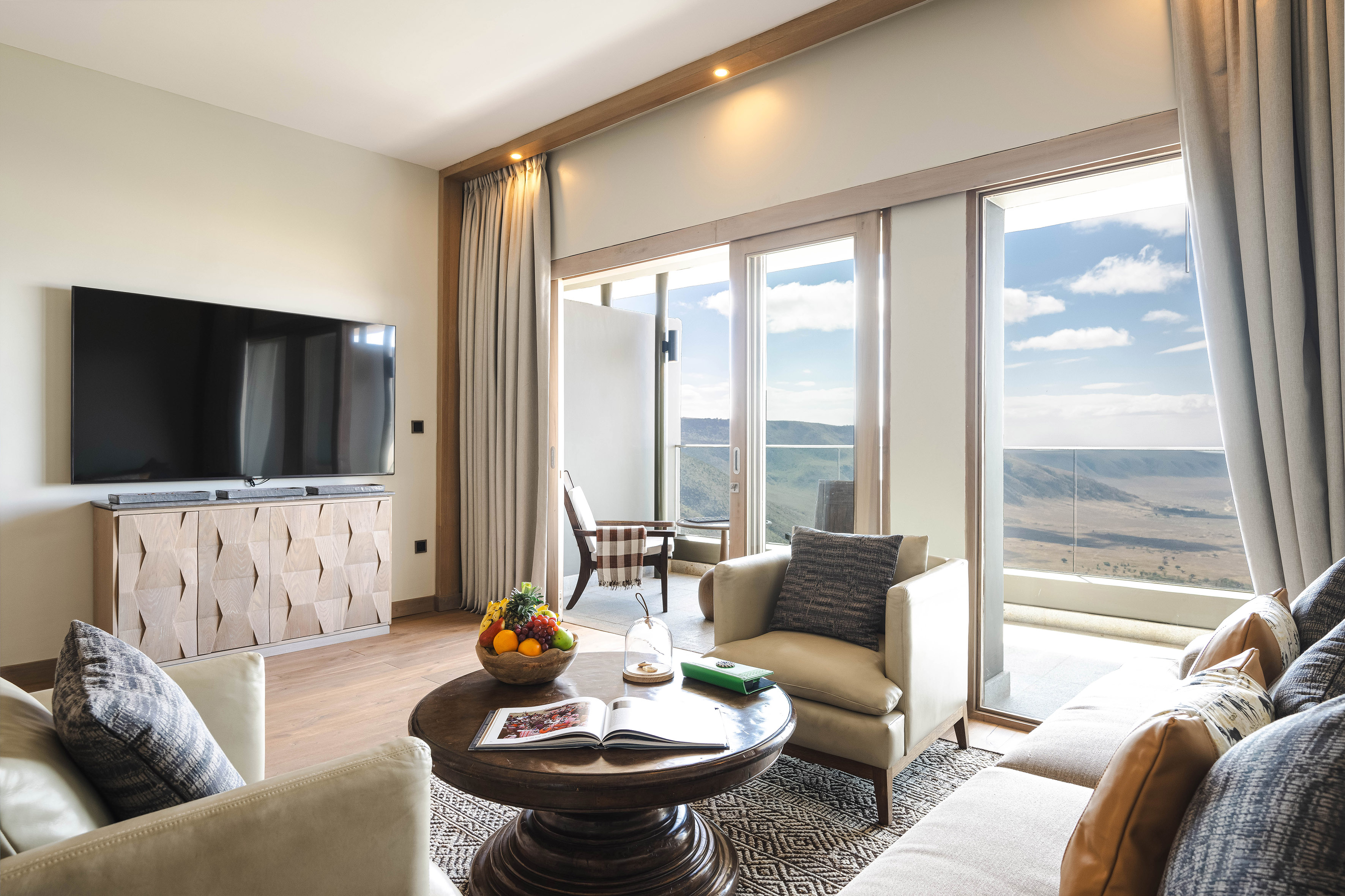 Luxury living room with balcony, TV, and panoramic valley view.