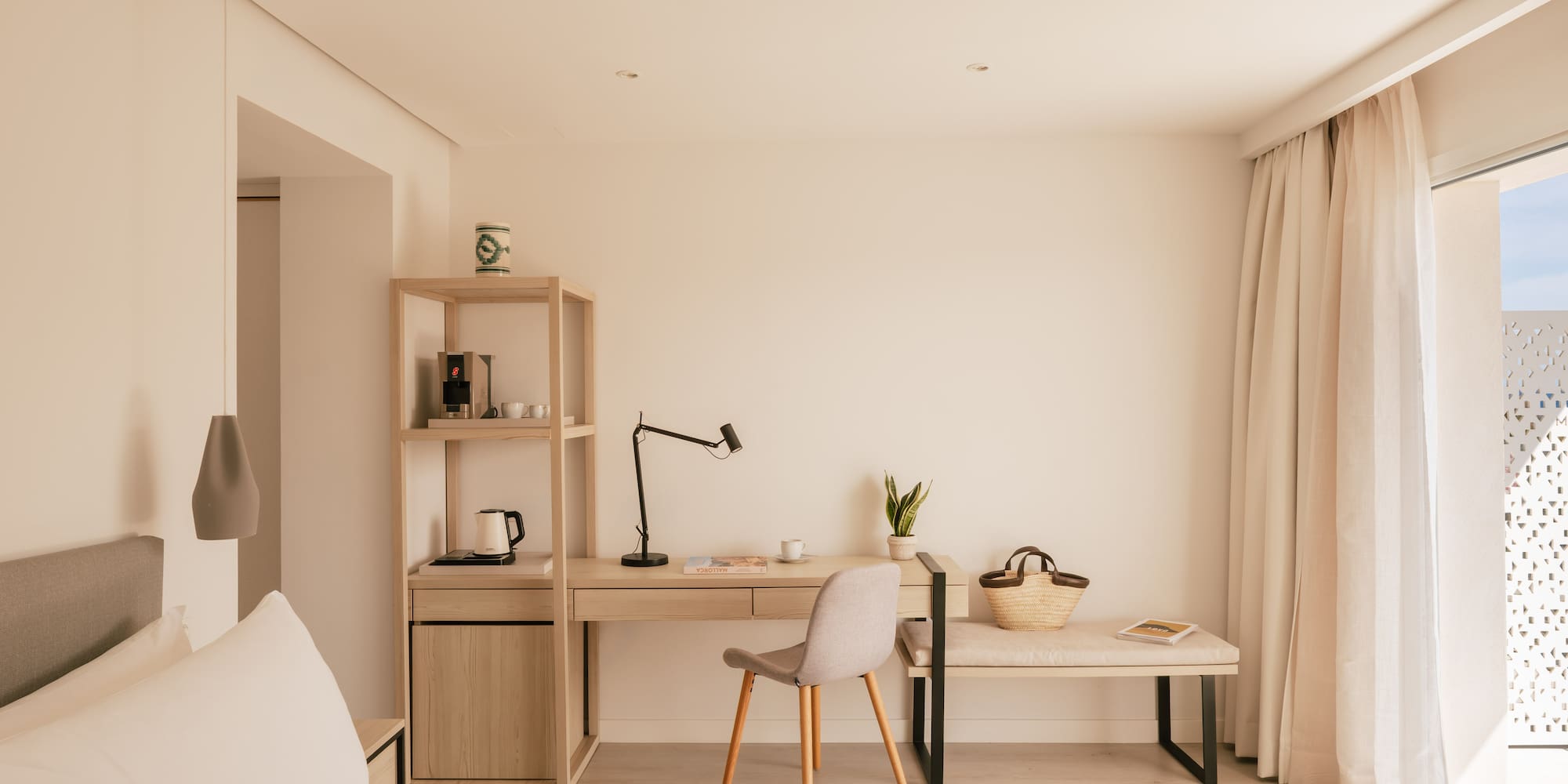 Bright, modern hotel room with minimalist desk, coffee station, and bed.