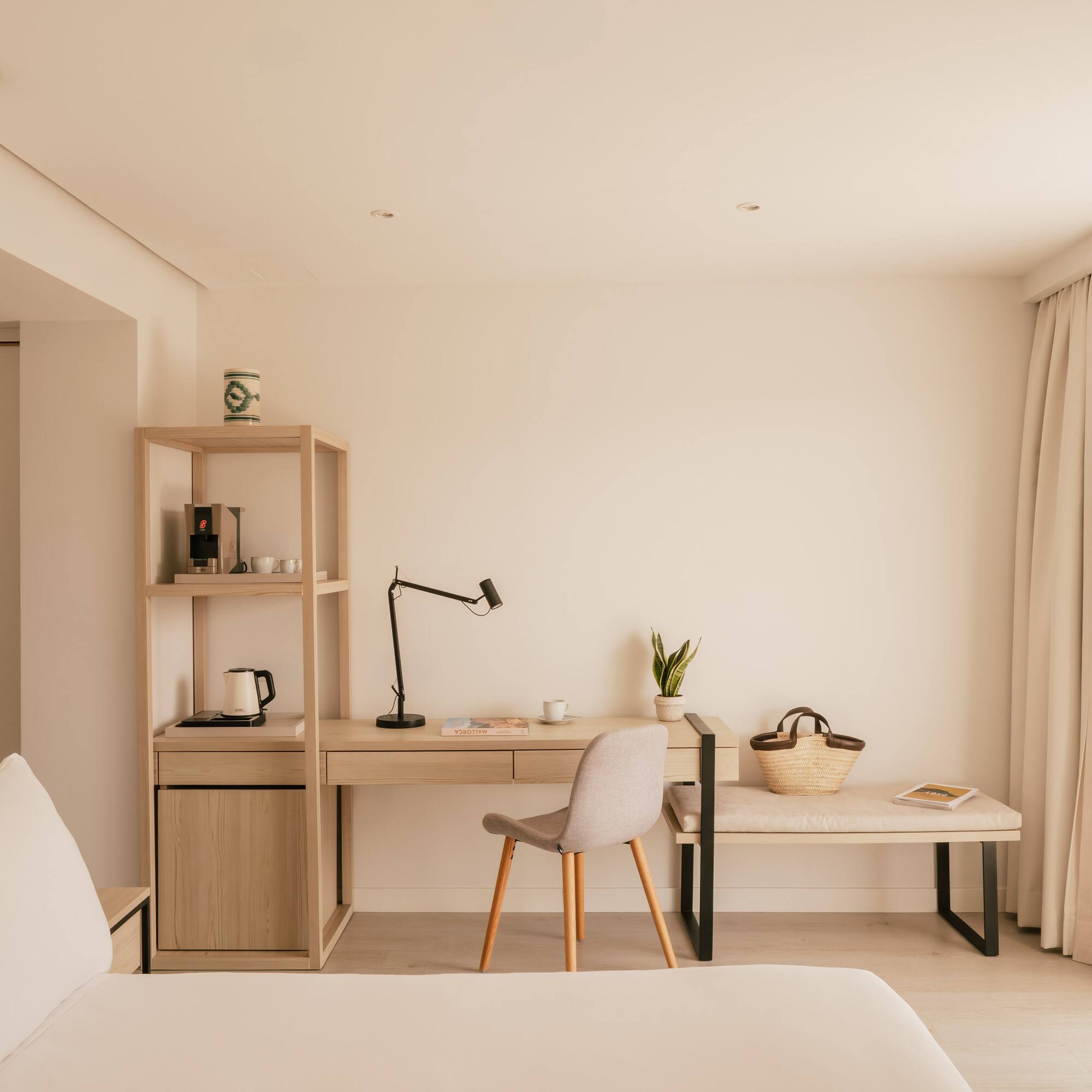 Bright, modern hotel room with minimalist desk, coffee station, and bed.