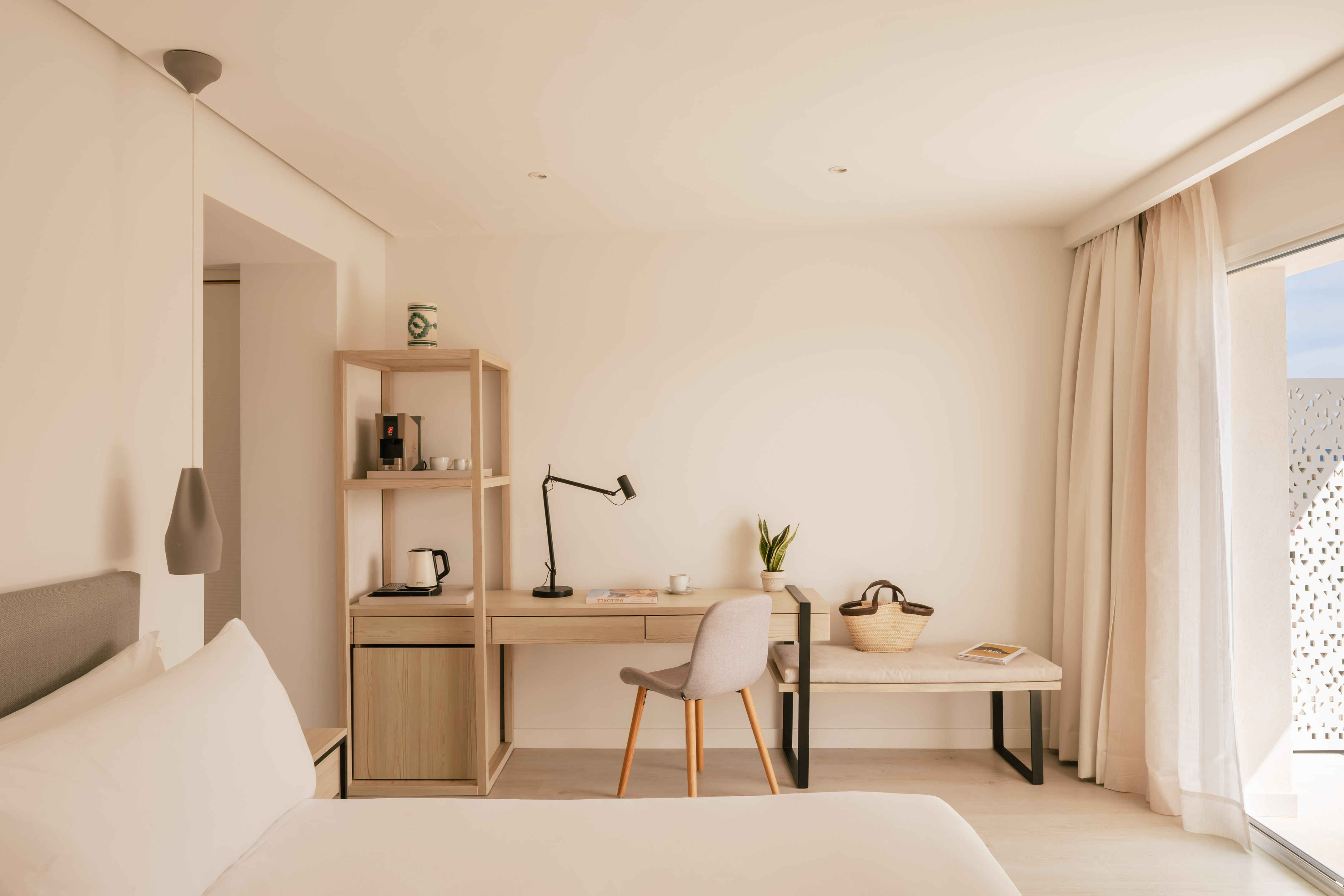Habitación de hotel moderna con escritorio, cafetera y diseño minimalista.